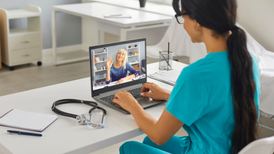 Patient waving hello on screen to doctor via a telehealth video call.