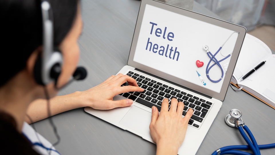 Person on laptop that says "Tele health" on the screen.
