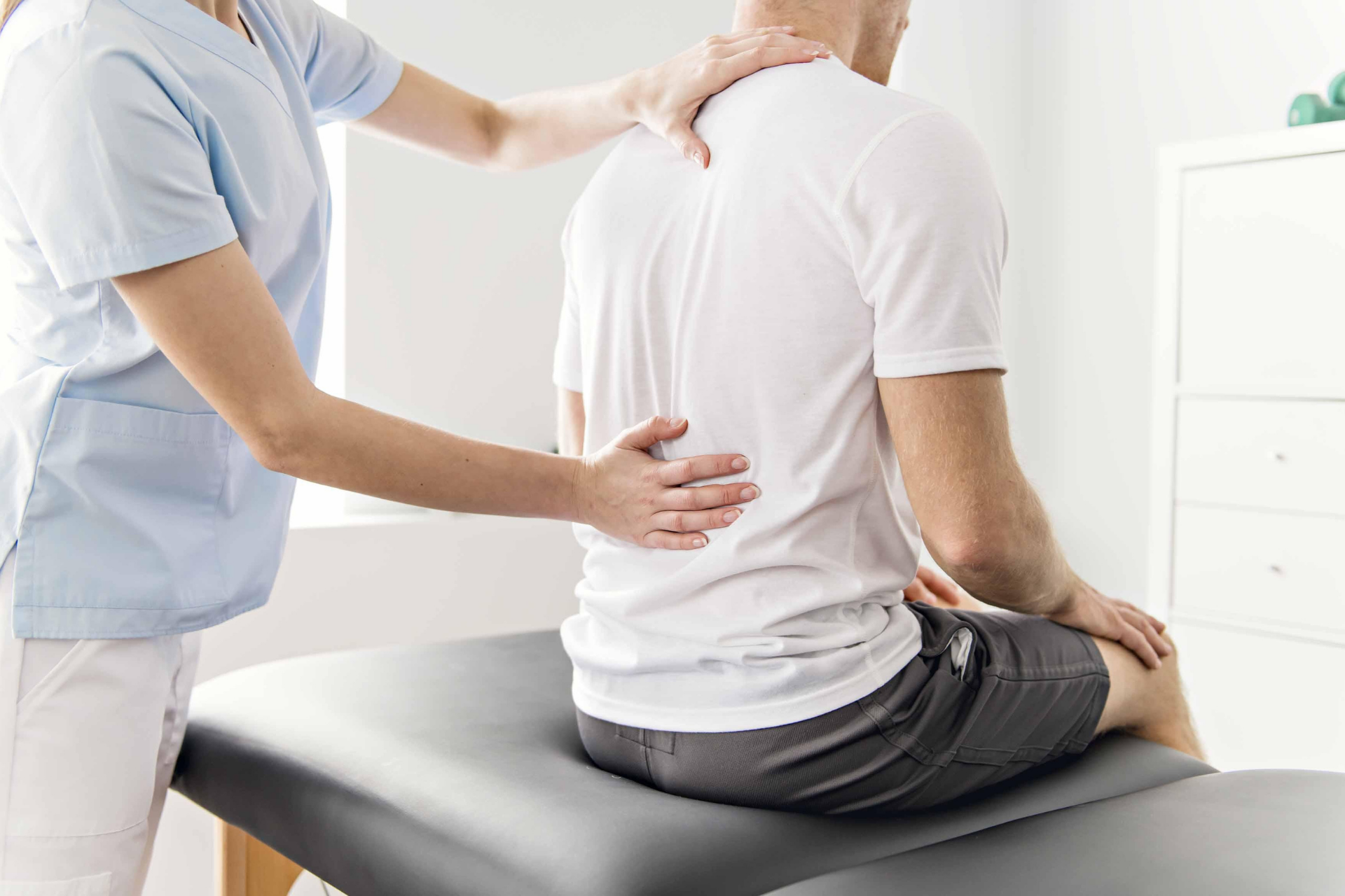 Therapist examining a man’s back during a physical therapy session