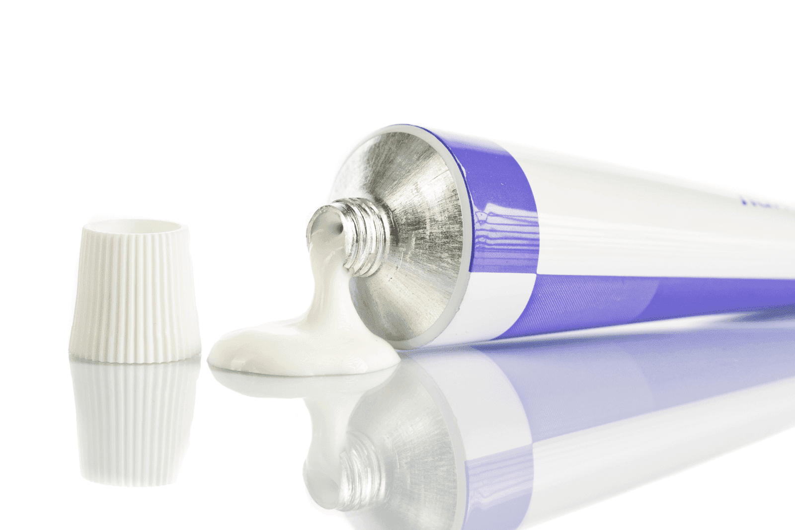 Tube of white cream squeezed onto a surface beside the cap.
