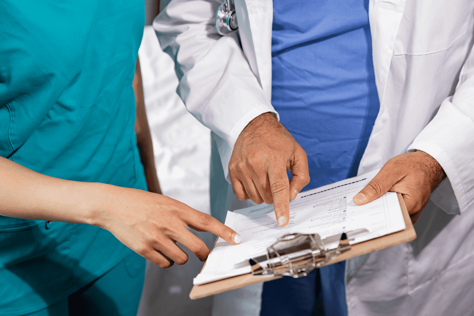 Two healthcare professionals pointing at a document on a clipboard.