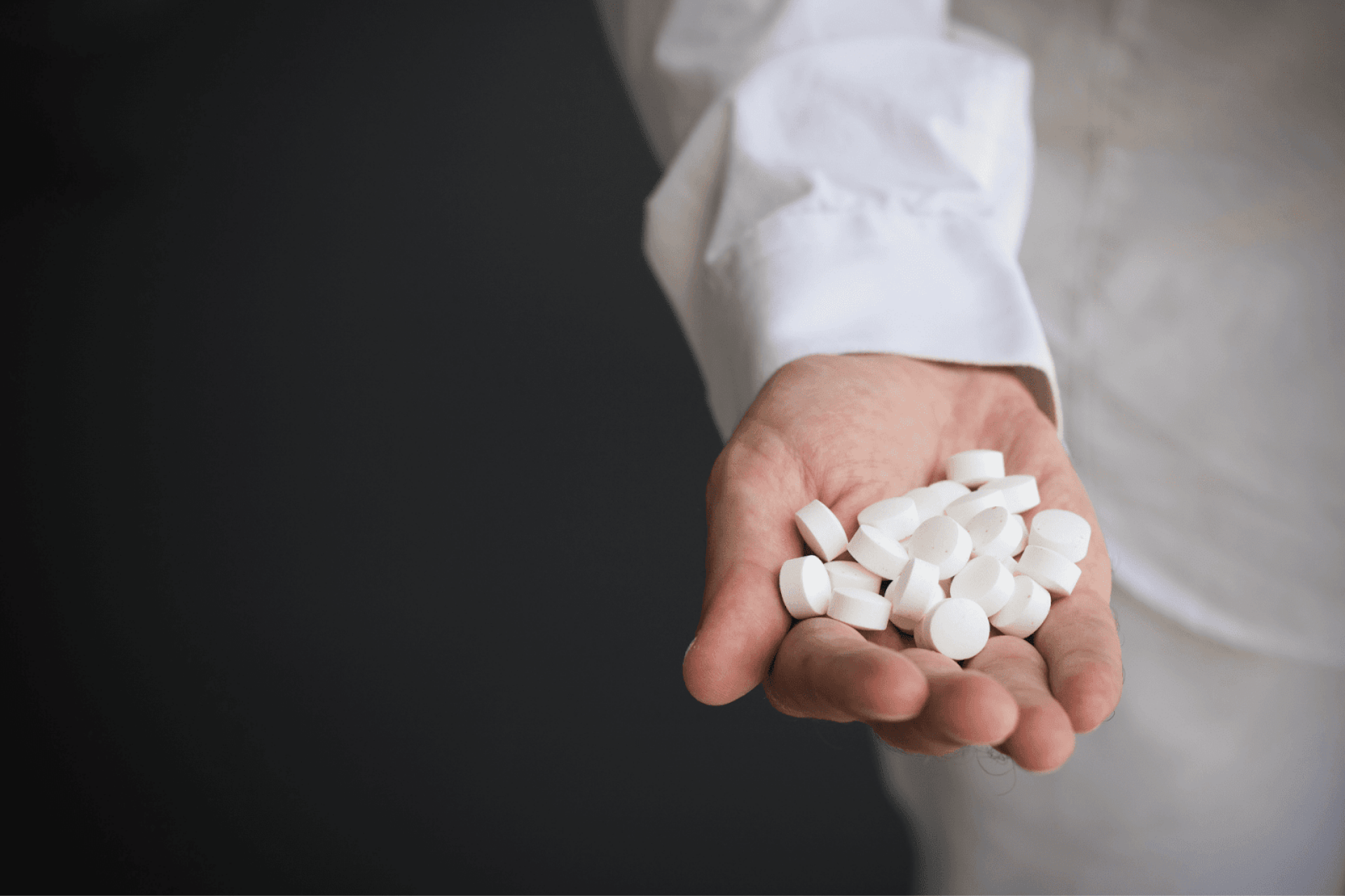 Hand holding white pills