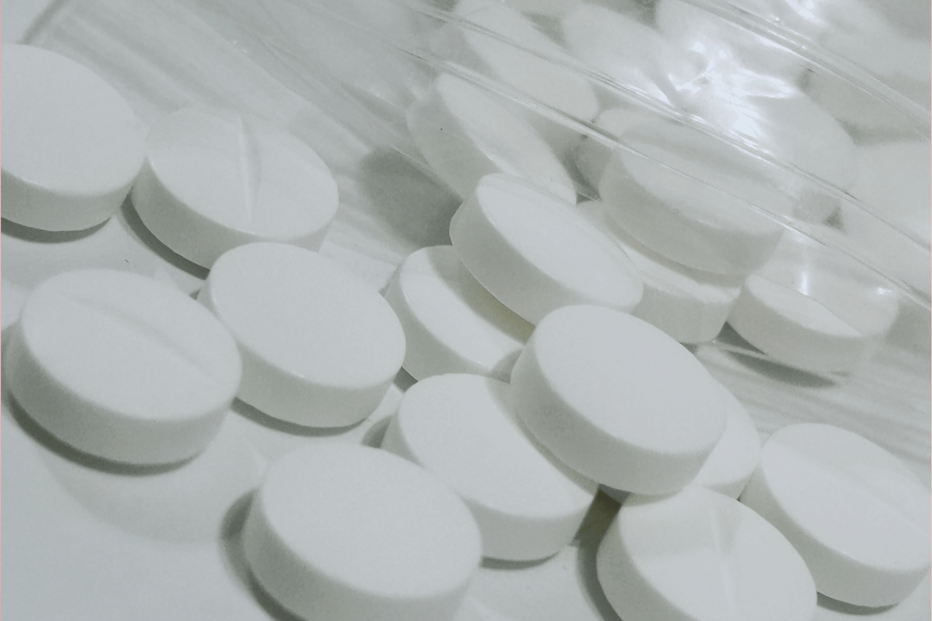 Close-up of white tablets spilled from a container.