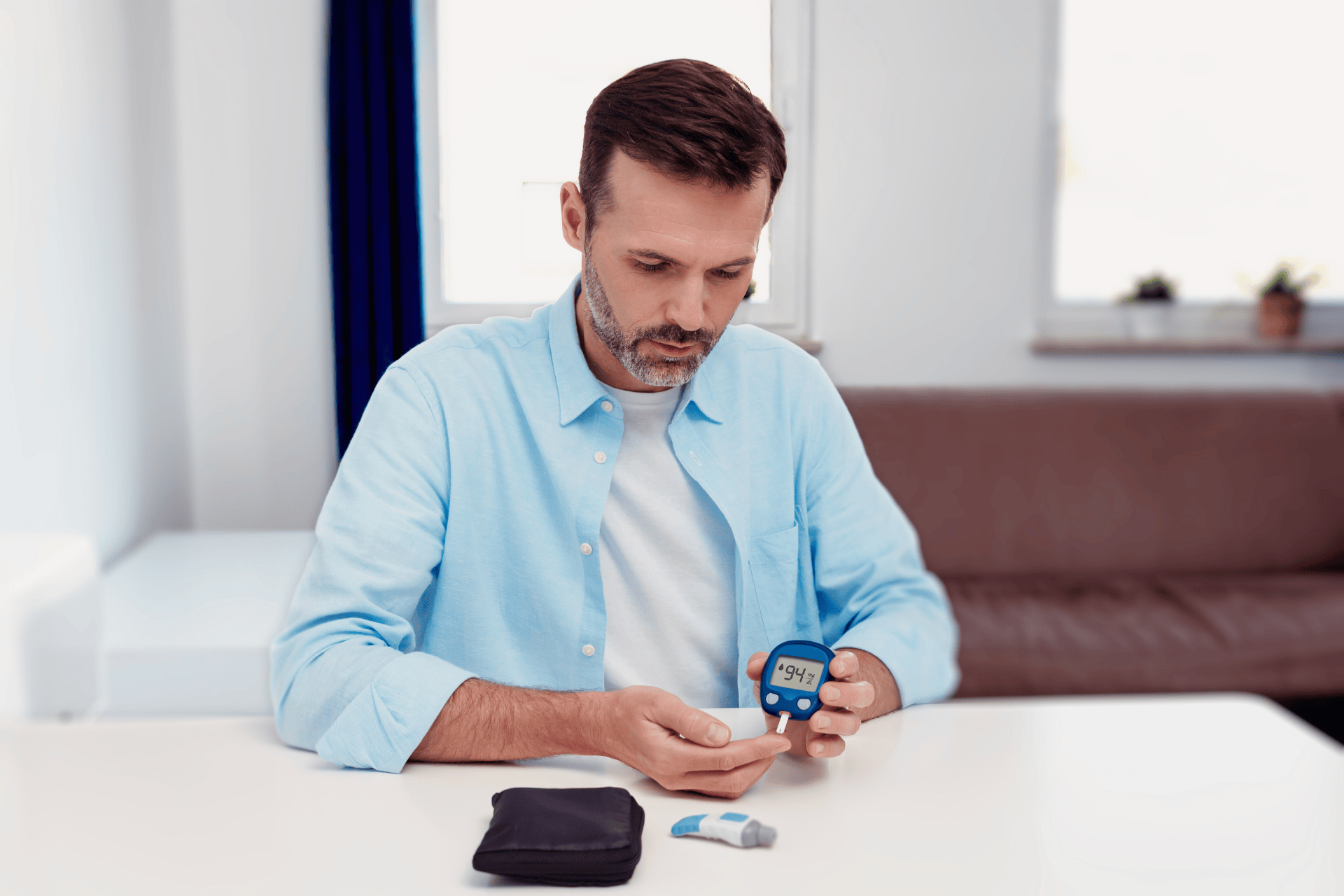 Man checking his blood sugar level with a glucose meter at home.