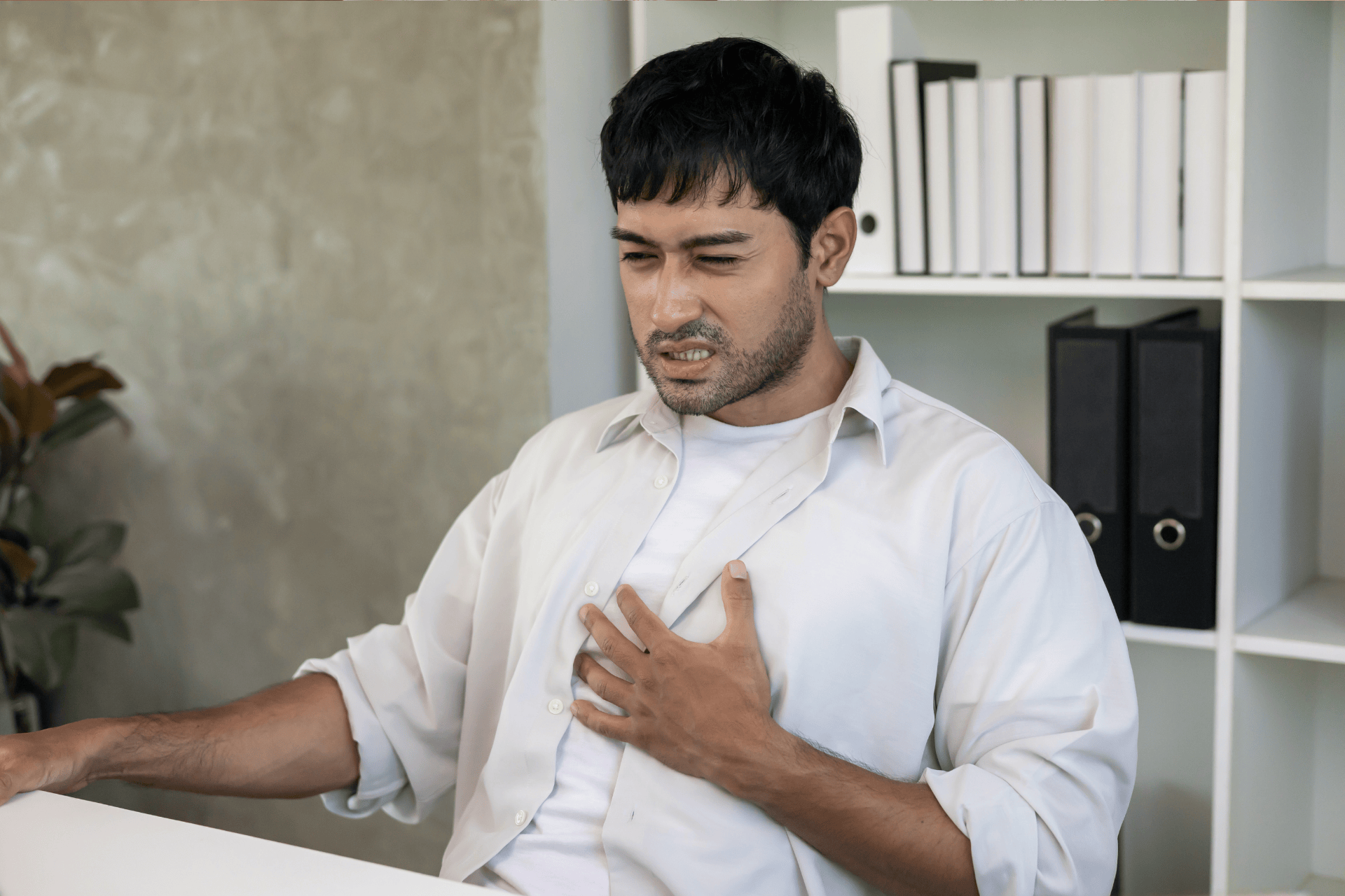 Man clutching his chest, appearing to experience chest pain.