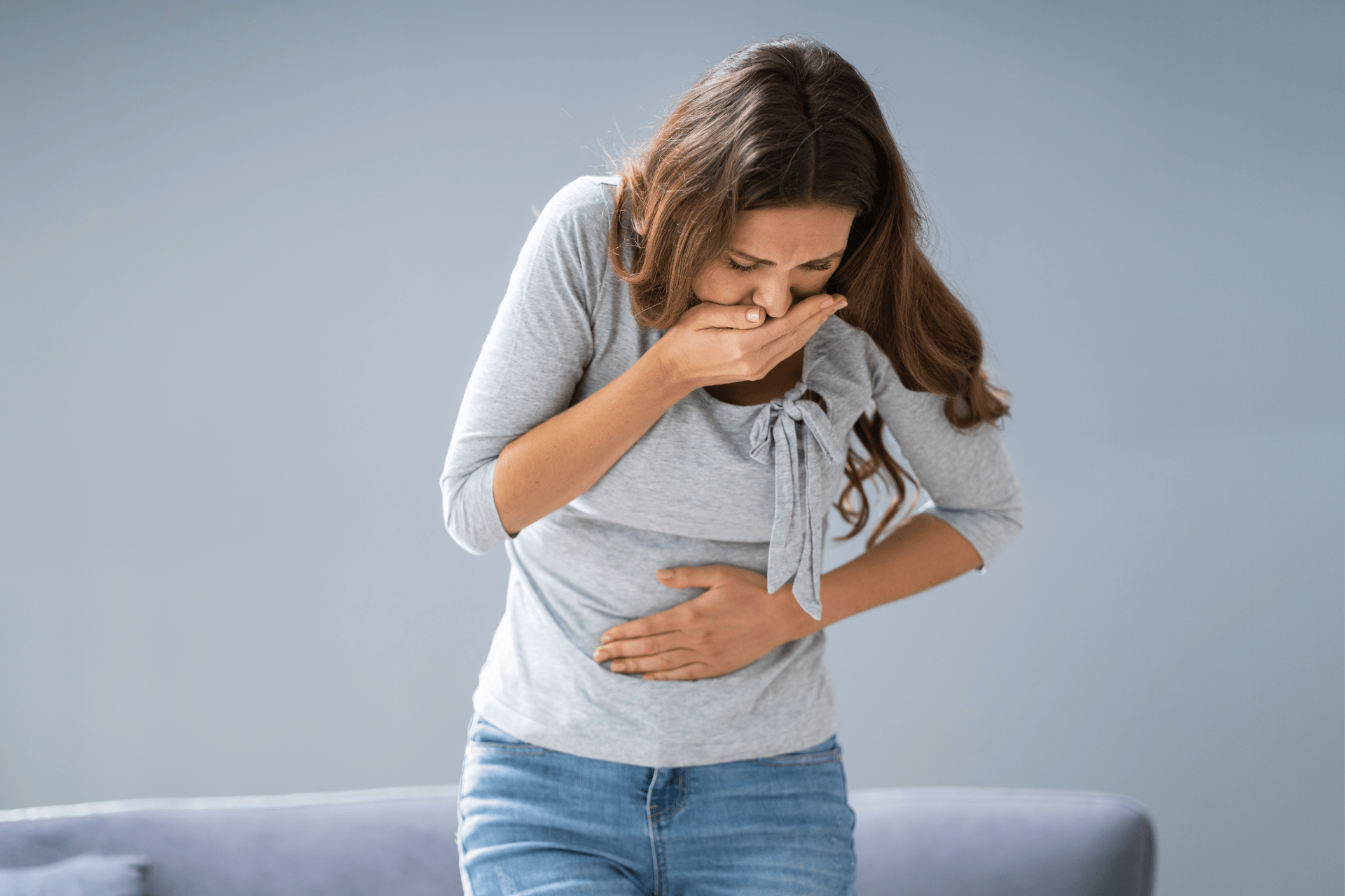 Woman covering her mouth and holding her stomach, appearing nauseous.