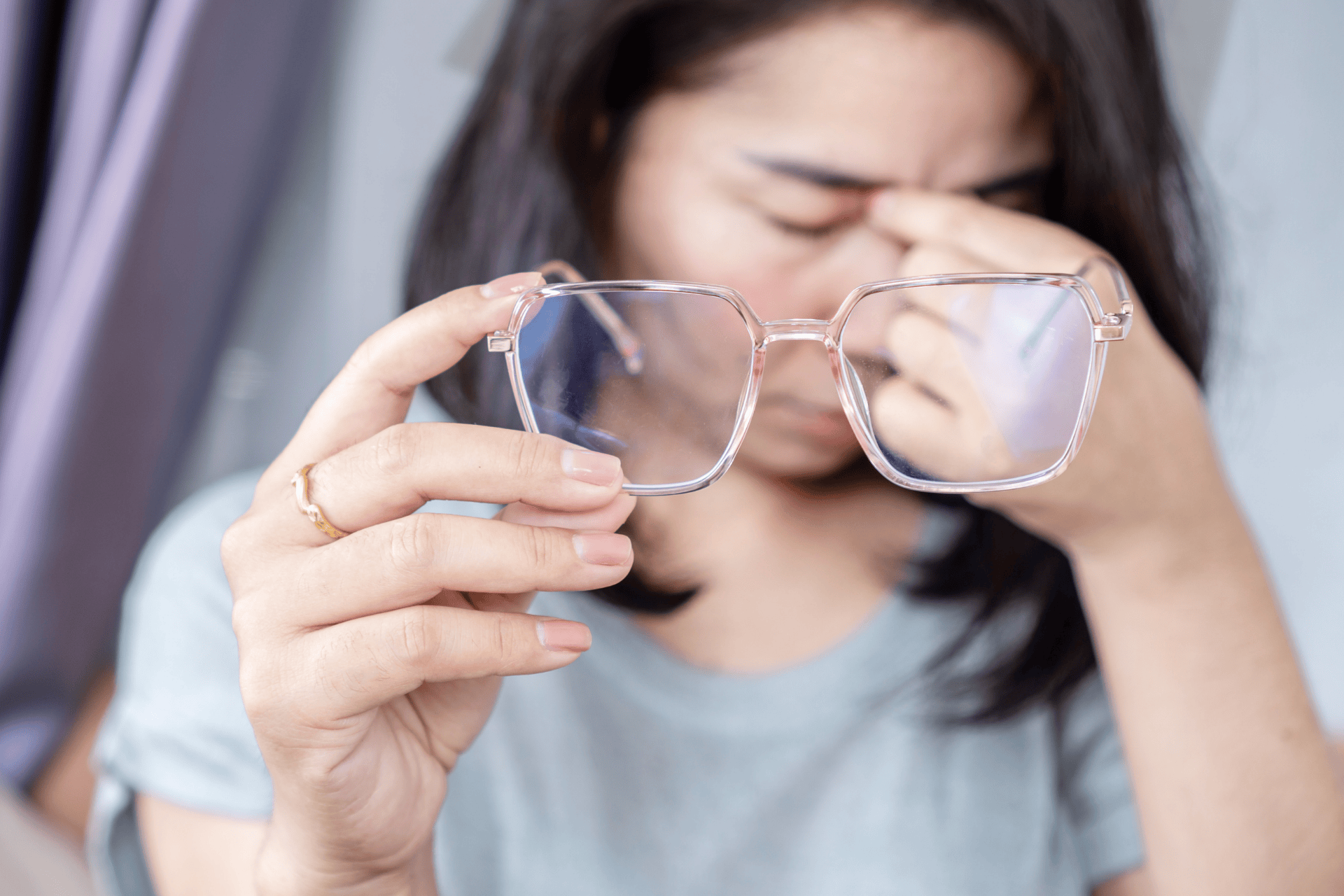 Woman holding her glasses and rubbing her eyes in discomfort.