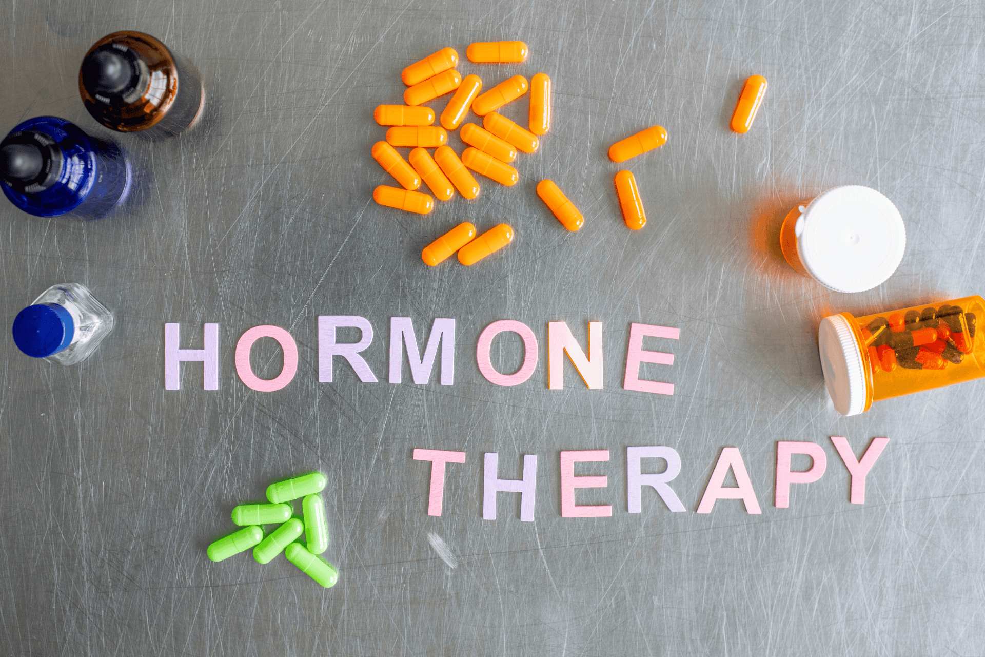 Colorful capsules and bottles arranged around the words ‘Hormone Therapy.’
