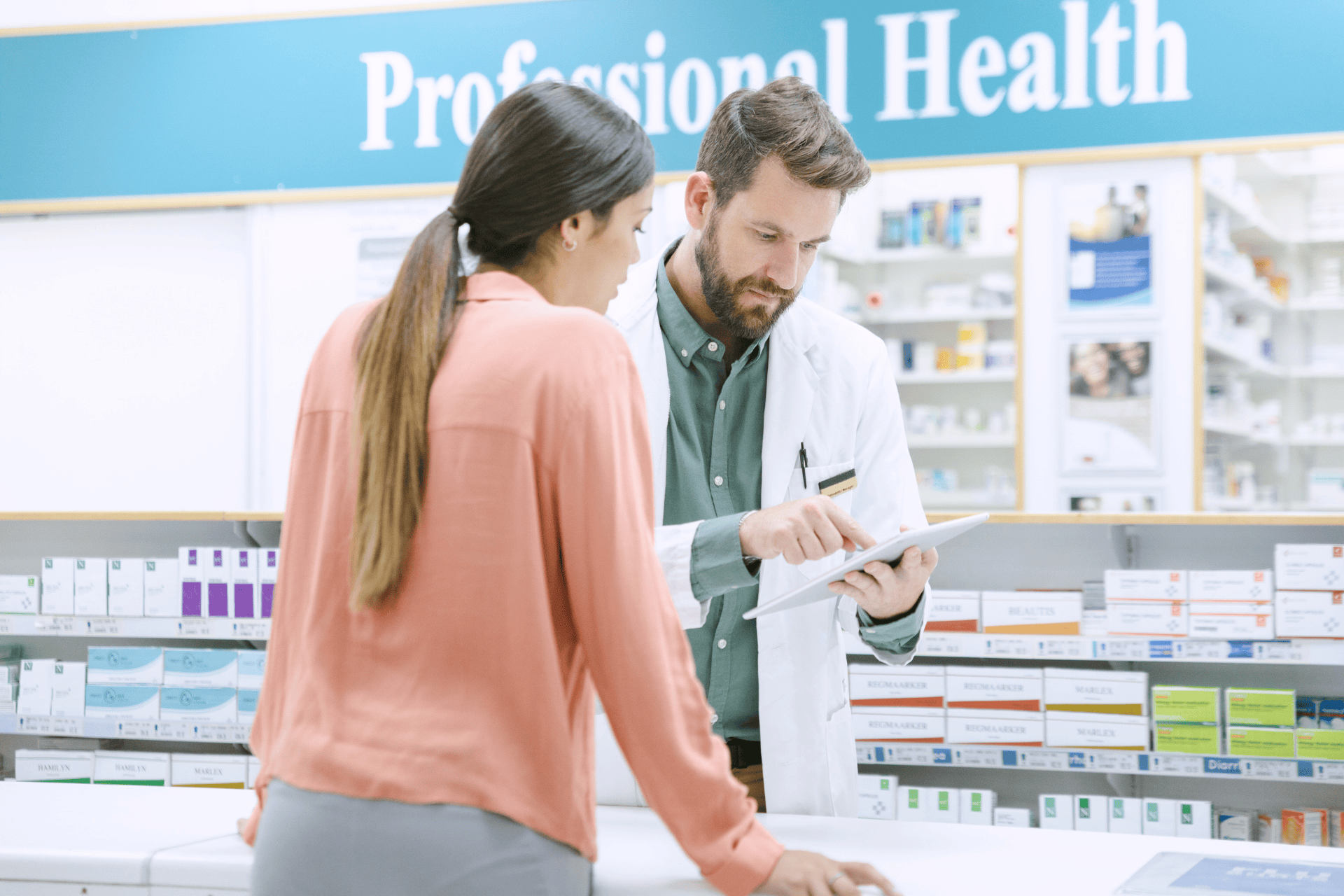 Pharmacist showing information on a tablet to a customer at the counter.