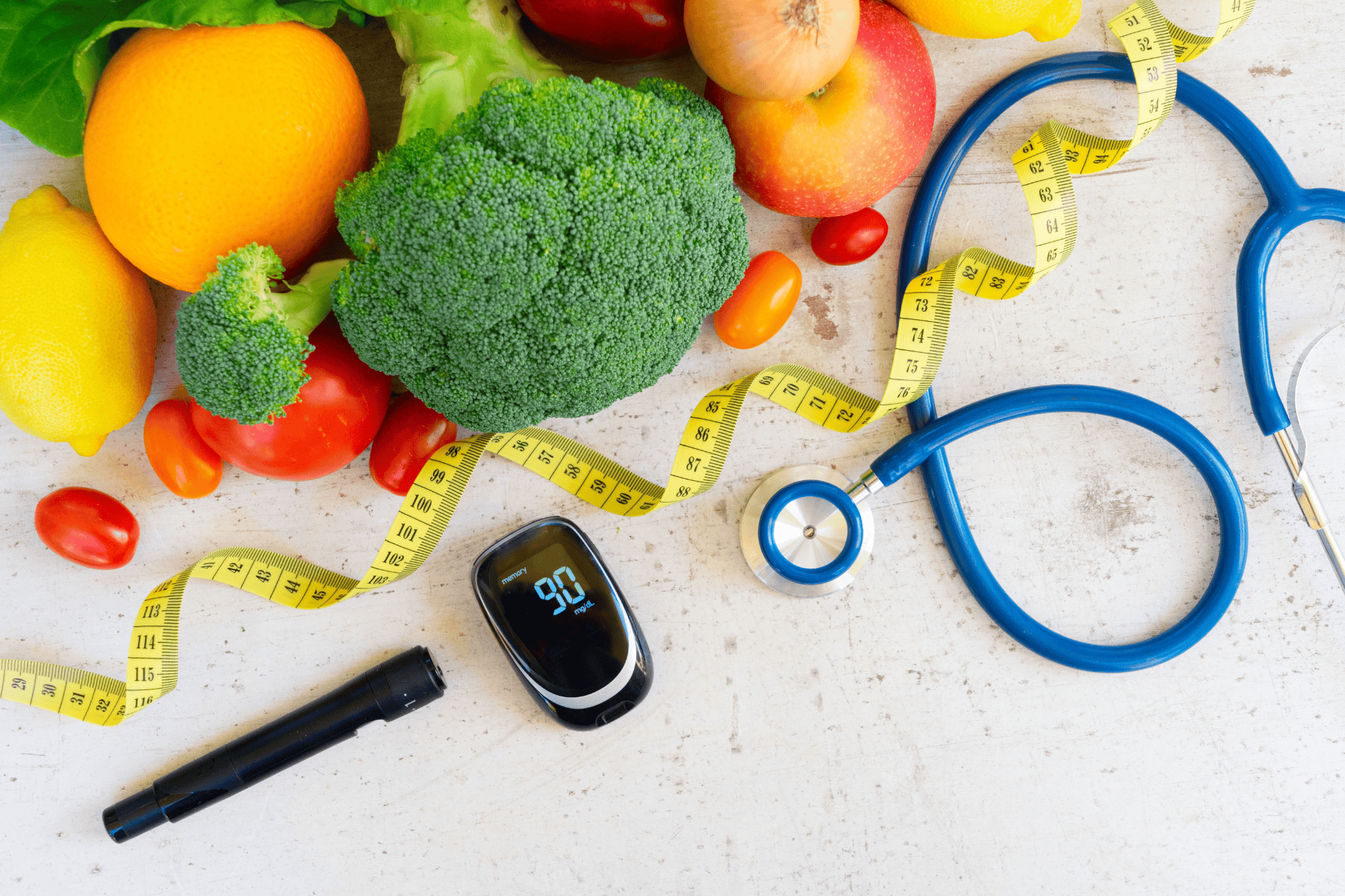 Fresh fruits and vegetables with a stethoscope, measuring tape, glucose meter, and insulin pen on a table.