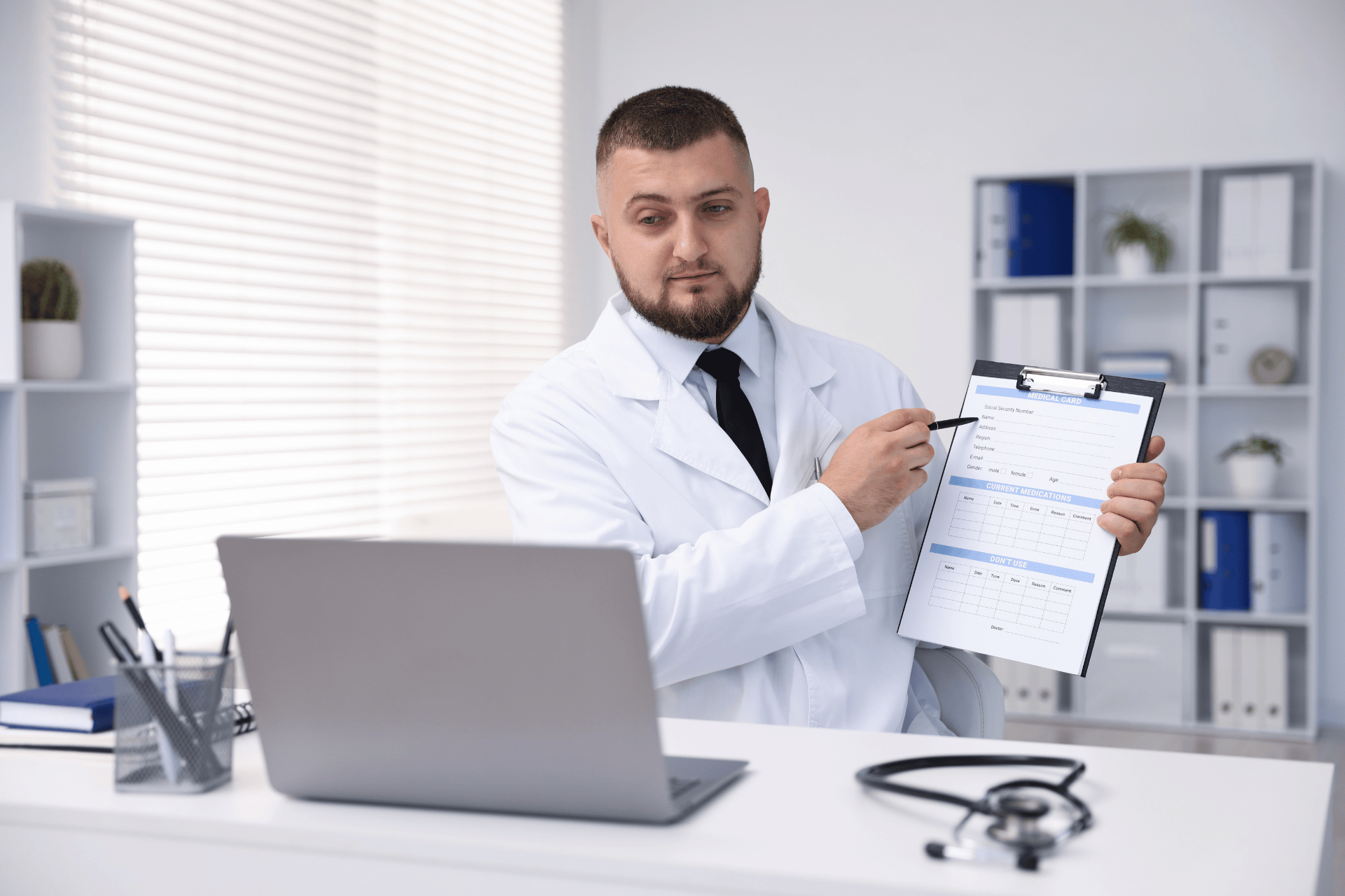Doctor in a white coat pointing at a medical form on a clipboard during a consultation.