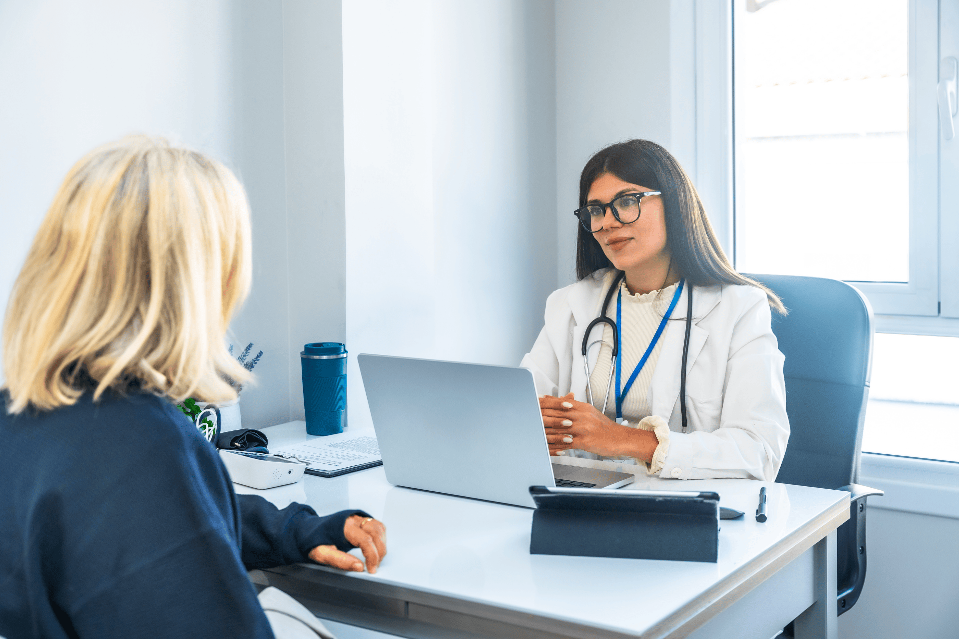 Female doctor talking with a patient at her desk during a medical consultation.