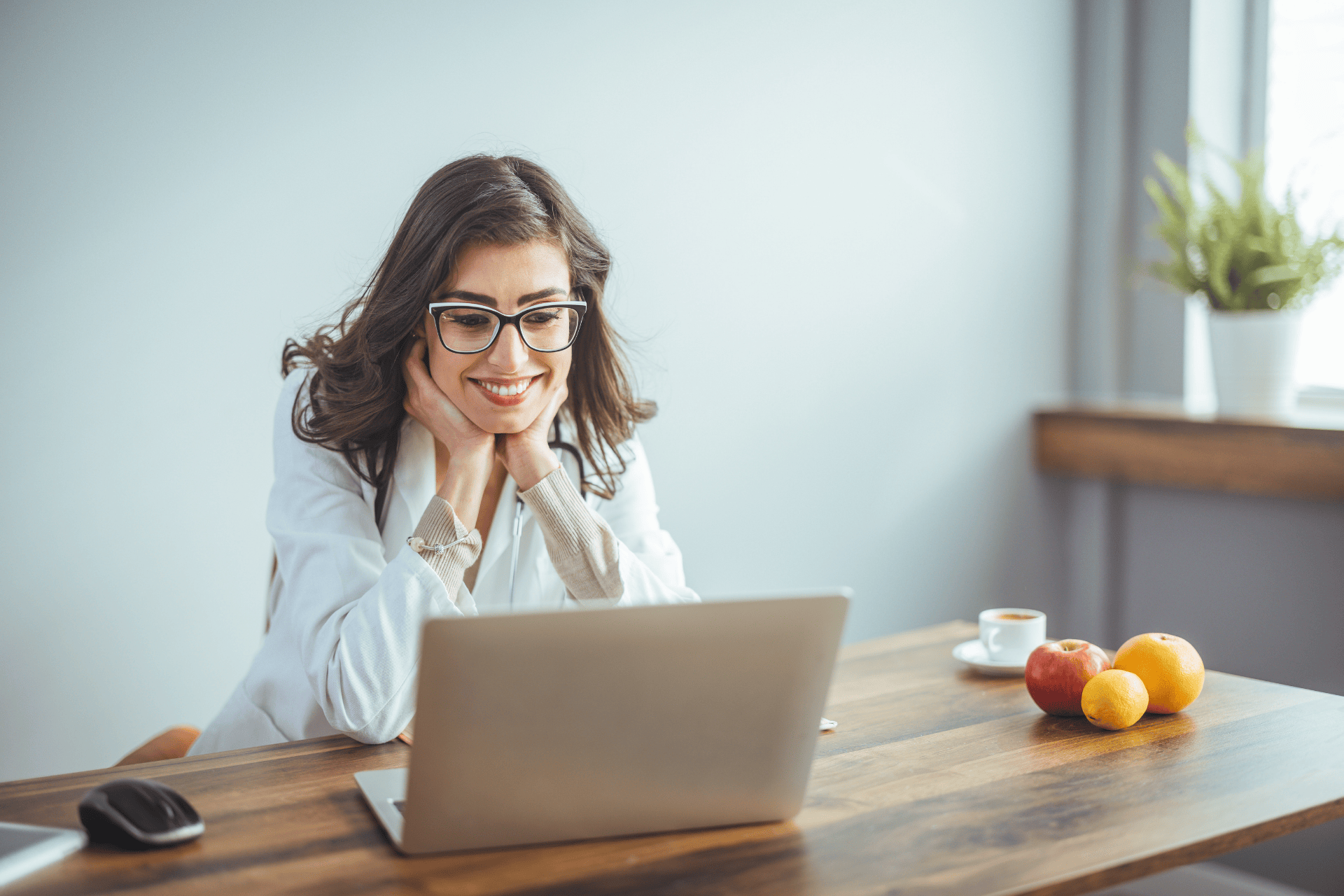Female doctor smiling at a laptop during an online consultation.