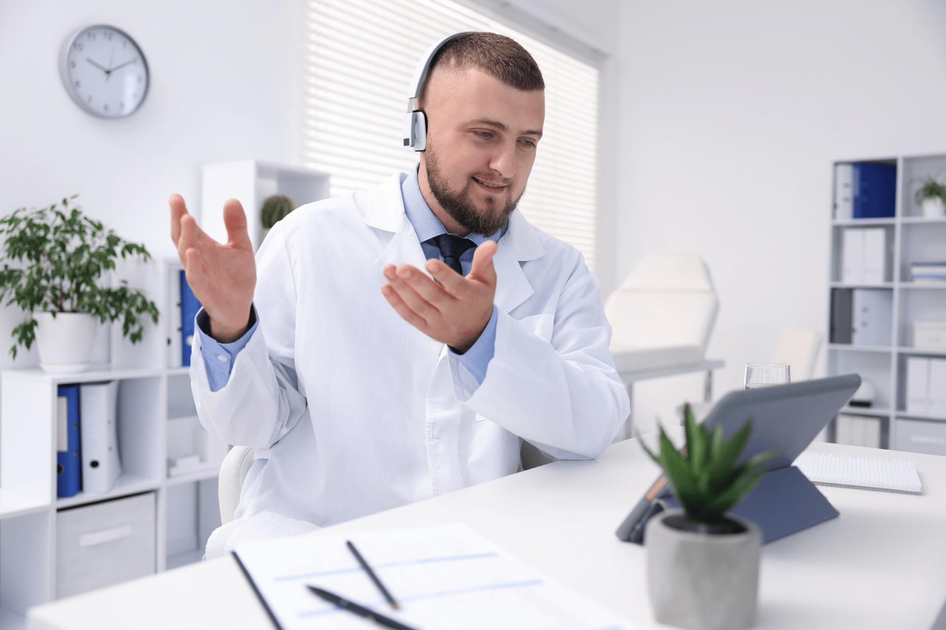Male doctor wearing a headset speaking during a video consultation.