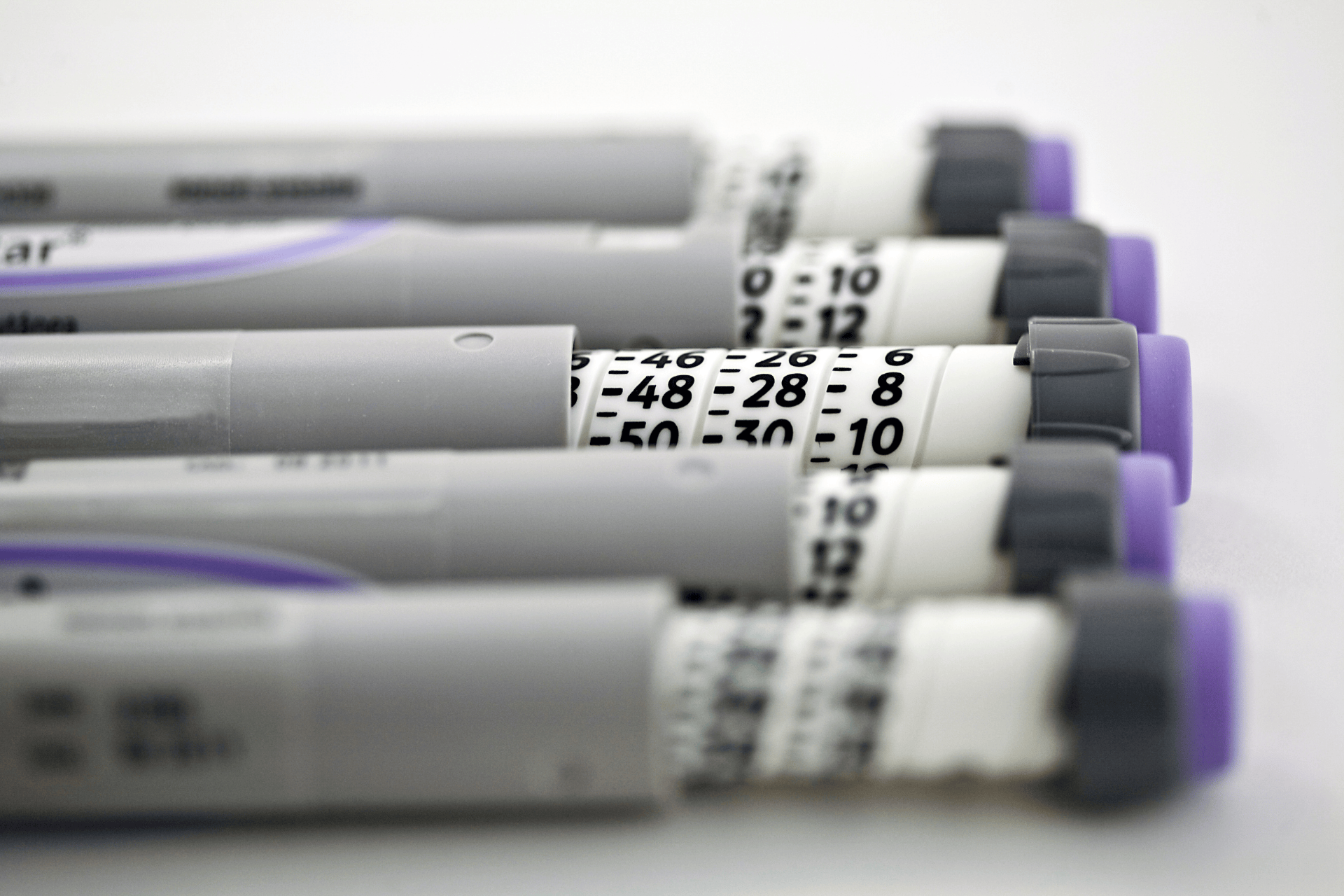 Close-up of several insulin pens arranged in a row.