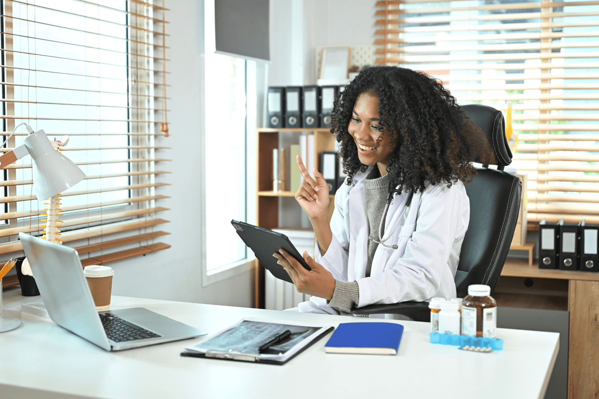 Smiling doctor holding a tablet during an online consultation.