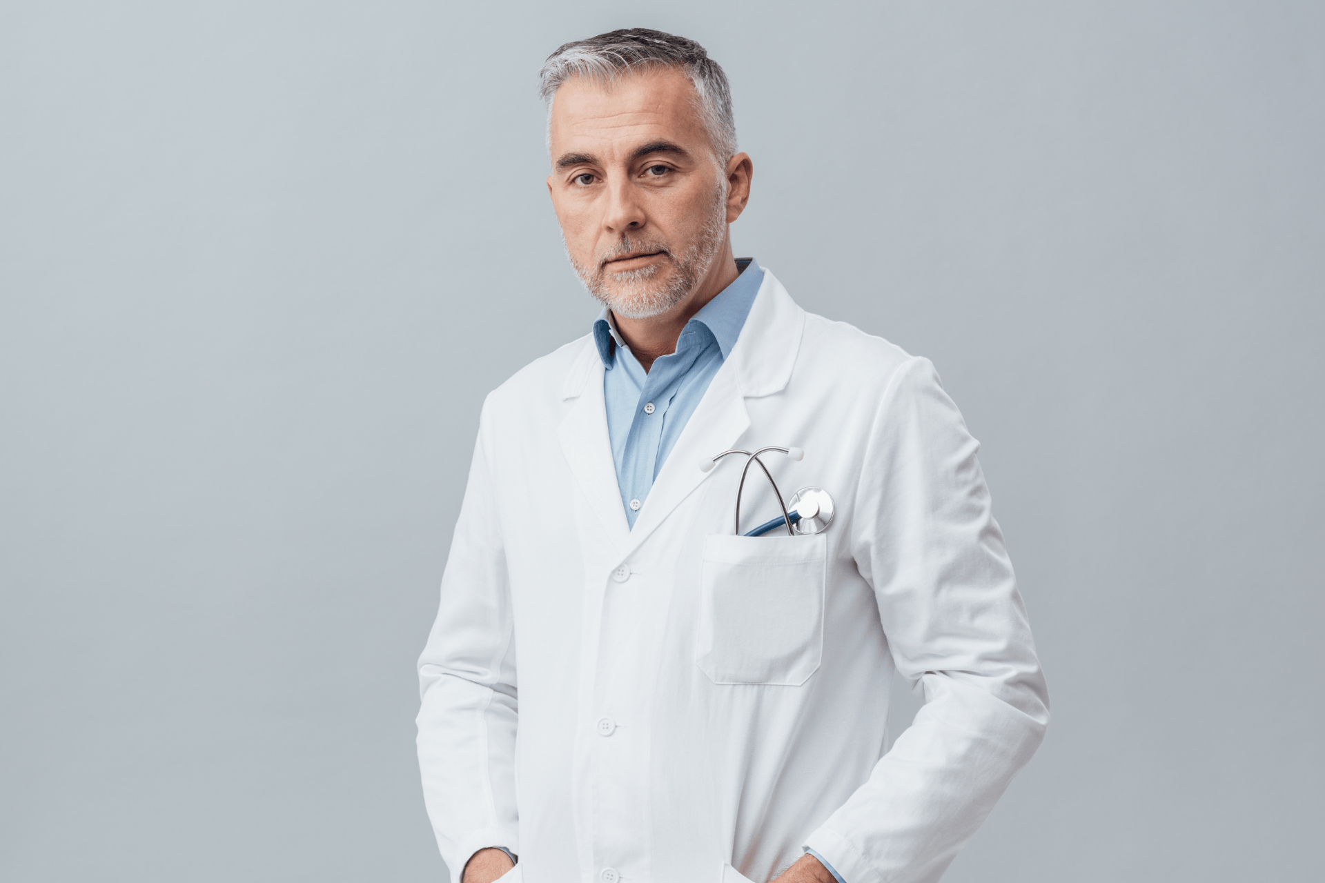 Male doctor in a white coat standing with a stethoscope in his pocket.