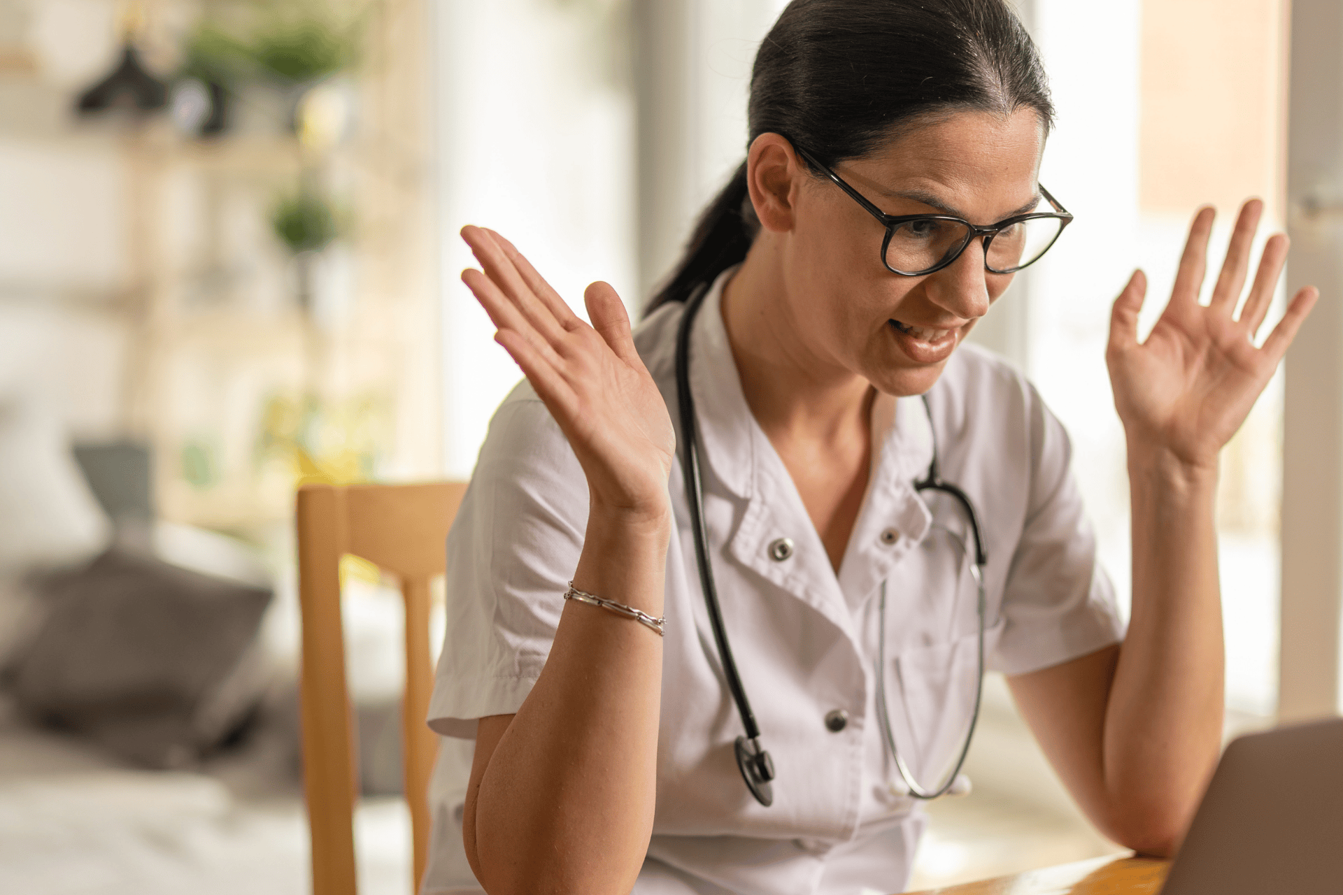 Doctor on a video call raising hands while talking.