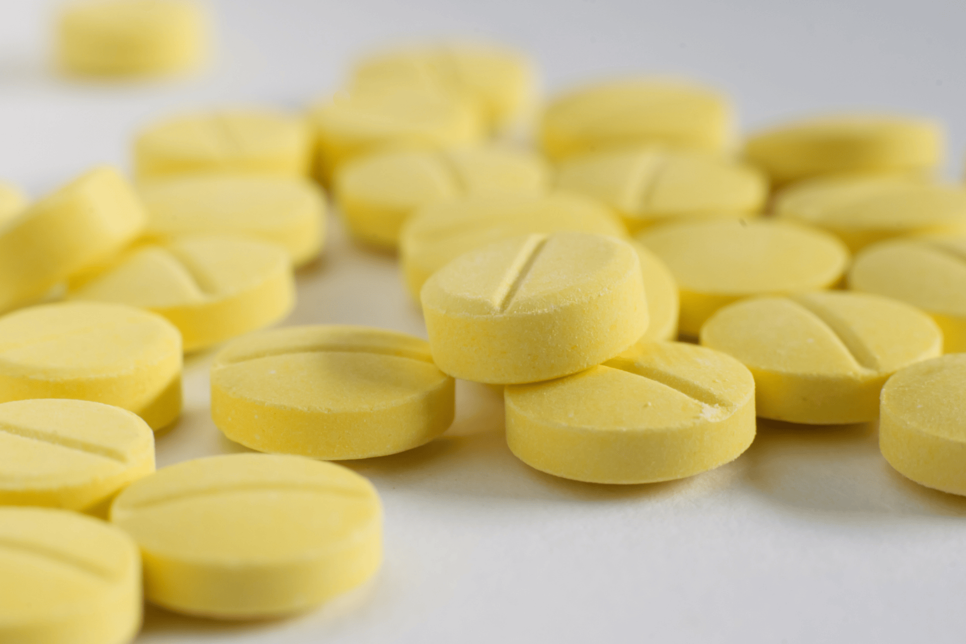 Close-up of yellow round tablets scattered on a white surface