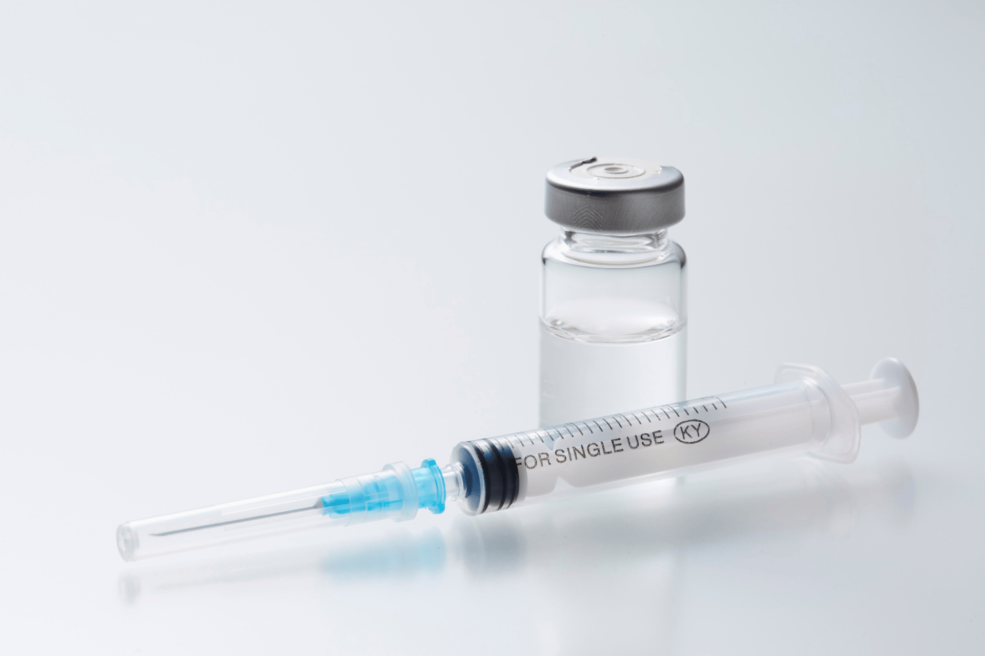 A vial of medication and a syringe used for Trimix injections on a clean white surface.