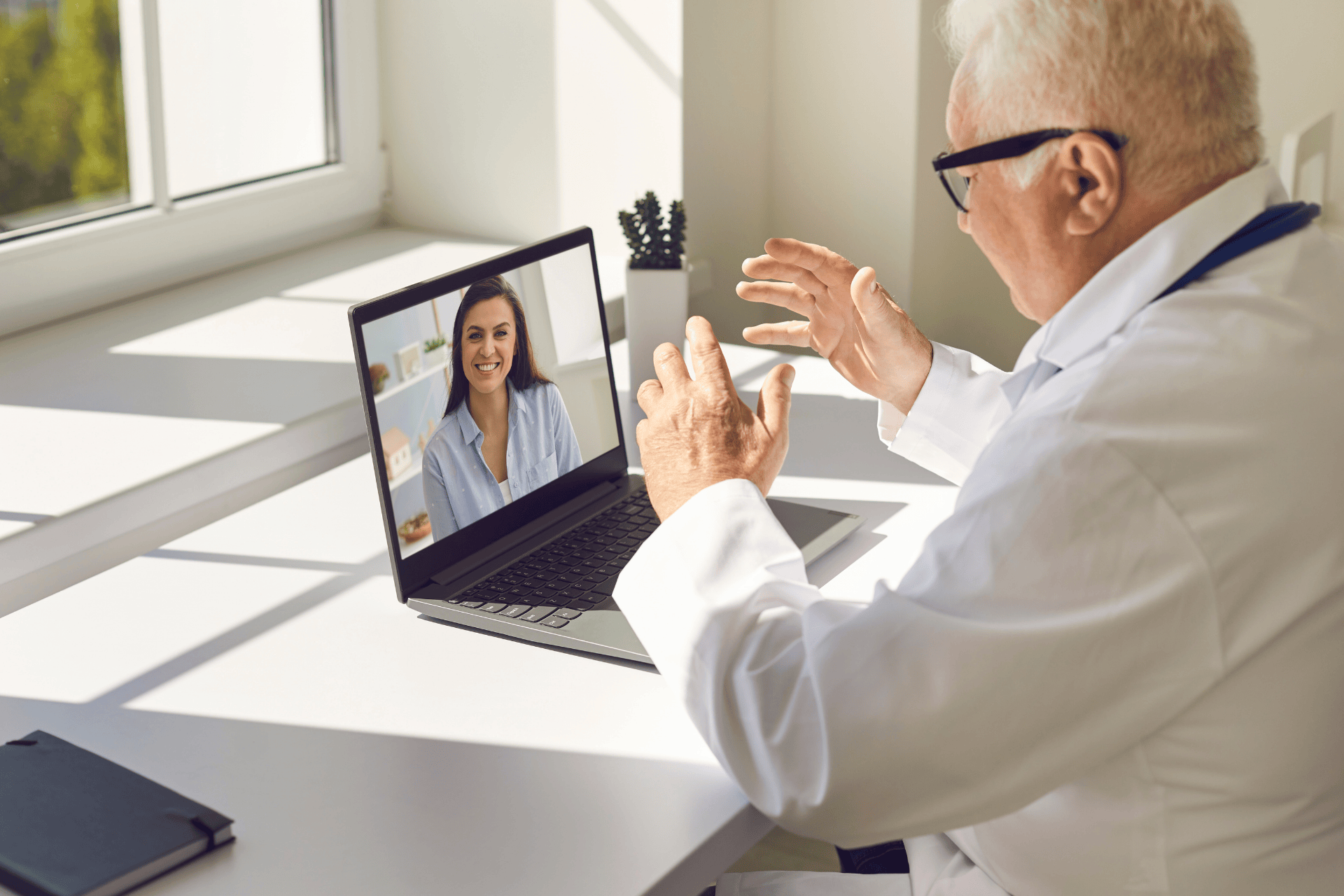 Doctor speaking with a smiling patient during an online video consultation on a laptop.