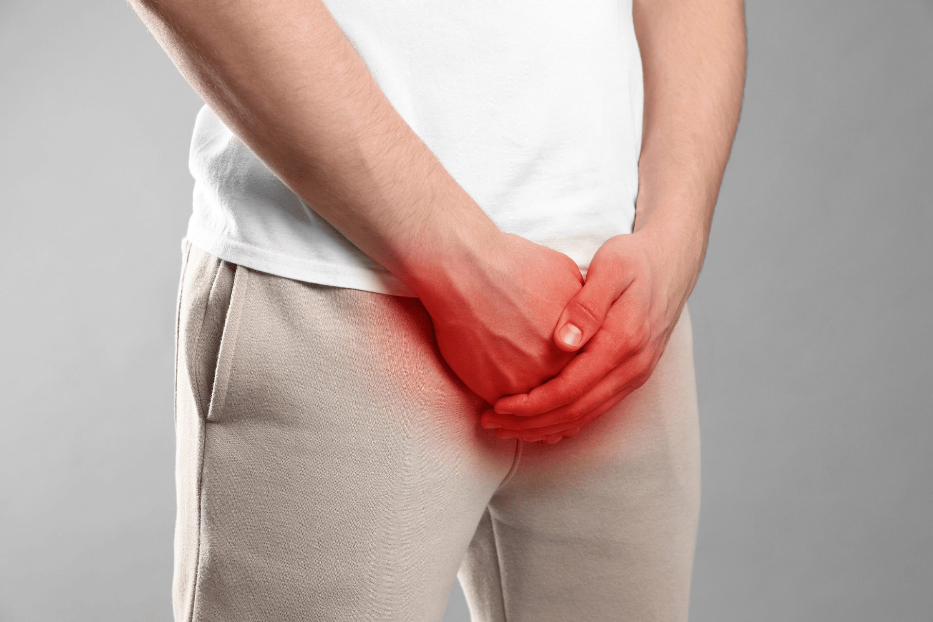 Man holding his groin area with a red highlight indicating discomfort.