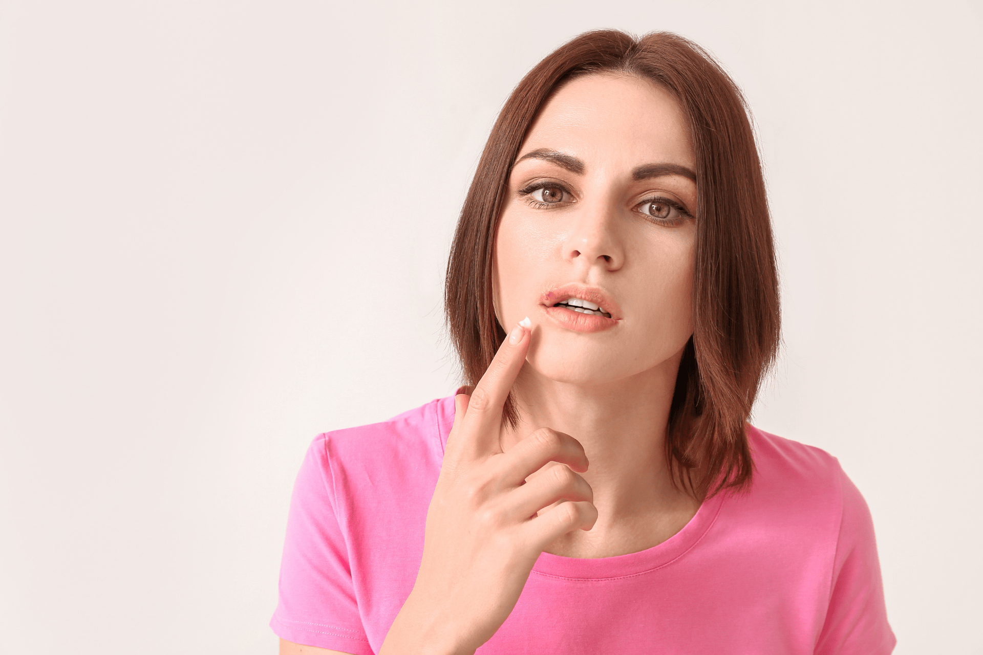 Woman applying cream to a sore spot on her lower lip.