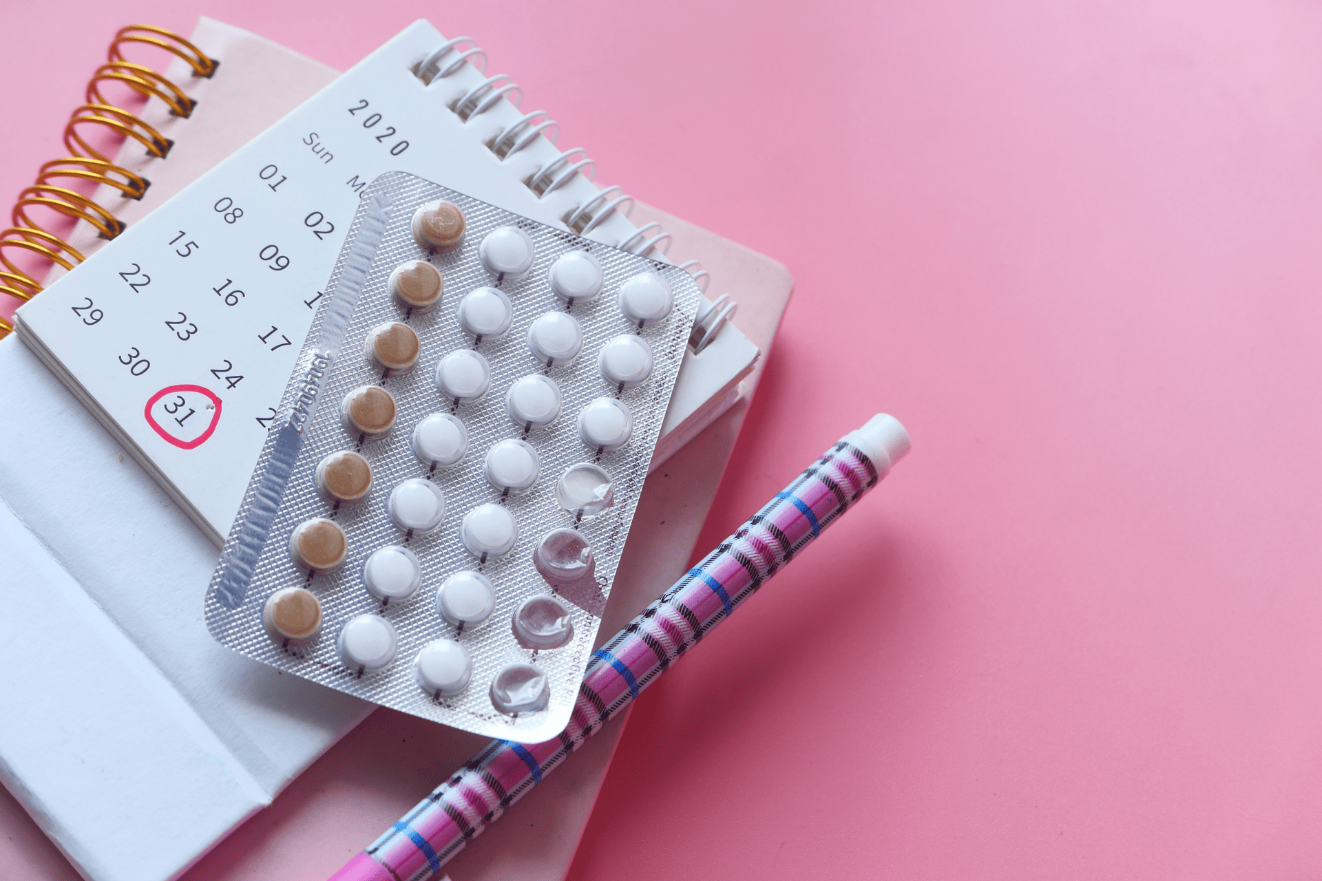 Birth control pill pack placed on top of a calendar with a date circled in red.