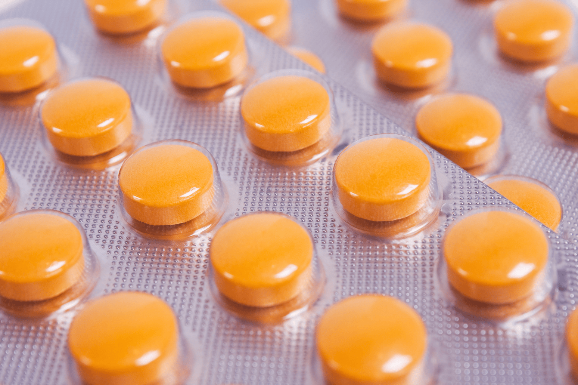 Close-up view of orange round tablets packaged in silver blister packs.