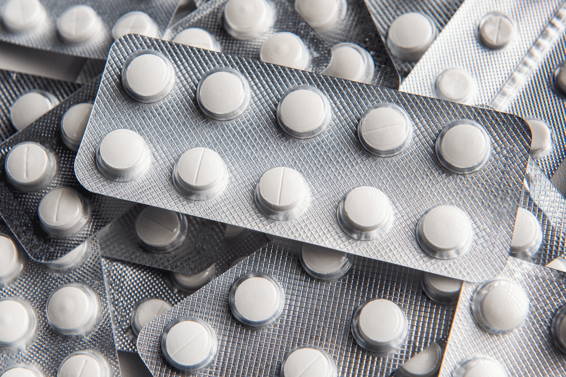 Stacked blister packs filled with white round tablets.