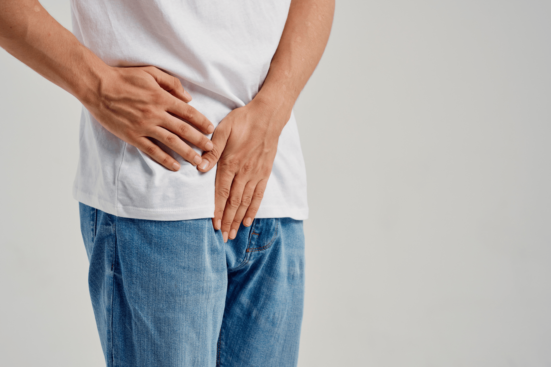 Man holding his lower abdomen and groin area, suggesting discomfort.