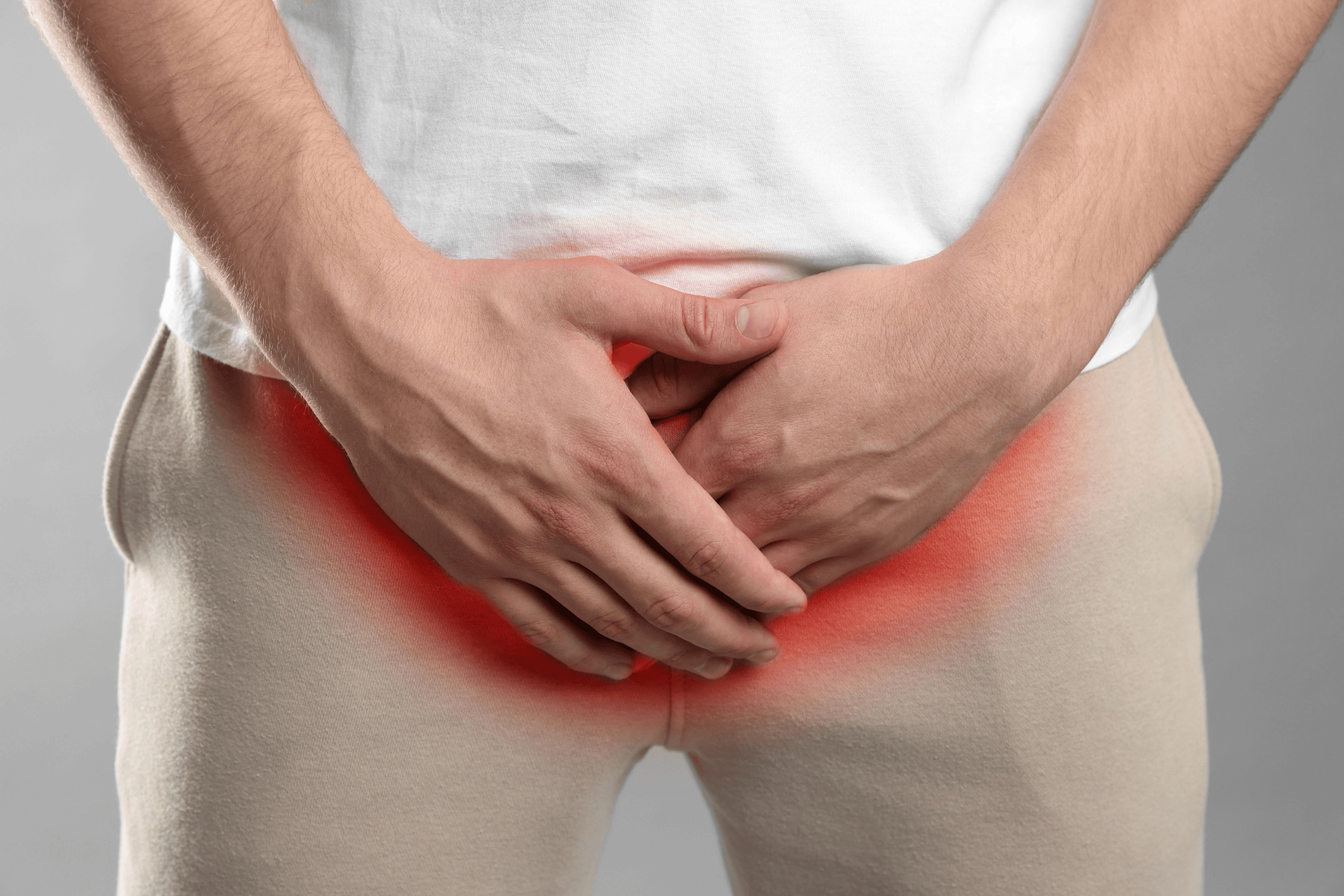 Person holding groin area with red highlight indicating pain or discomfort.
