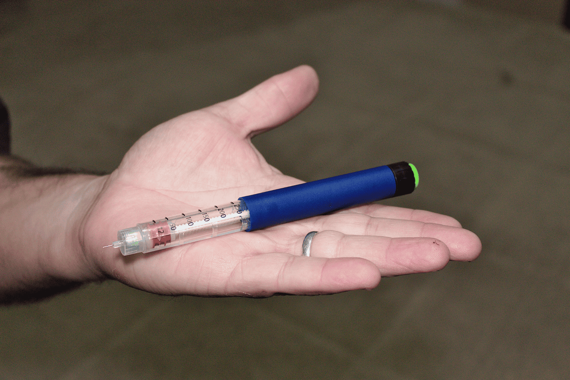 A hand holding an insulin pen.