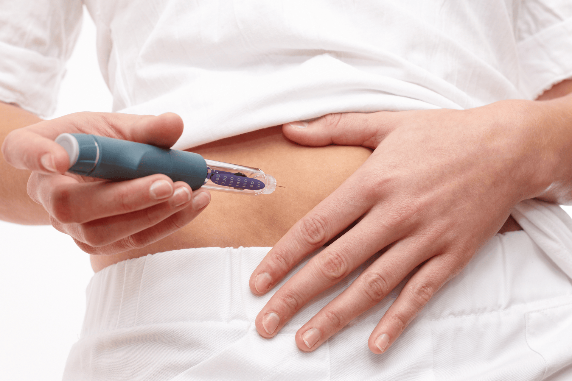 A person injecting medication into their abdomen with an injection pen.