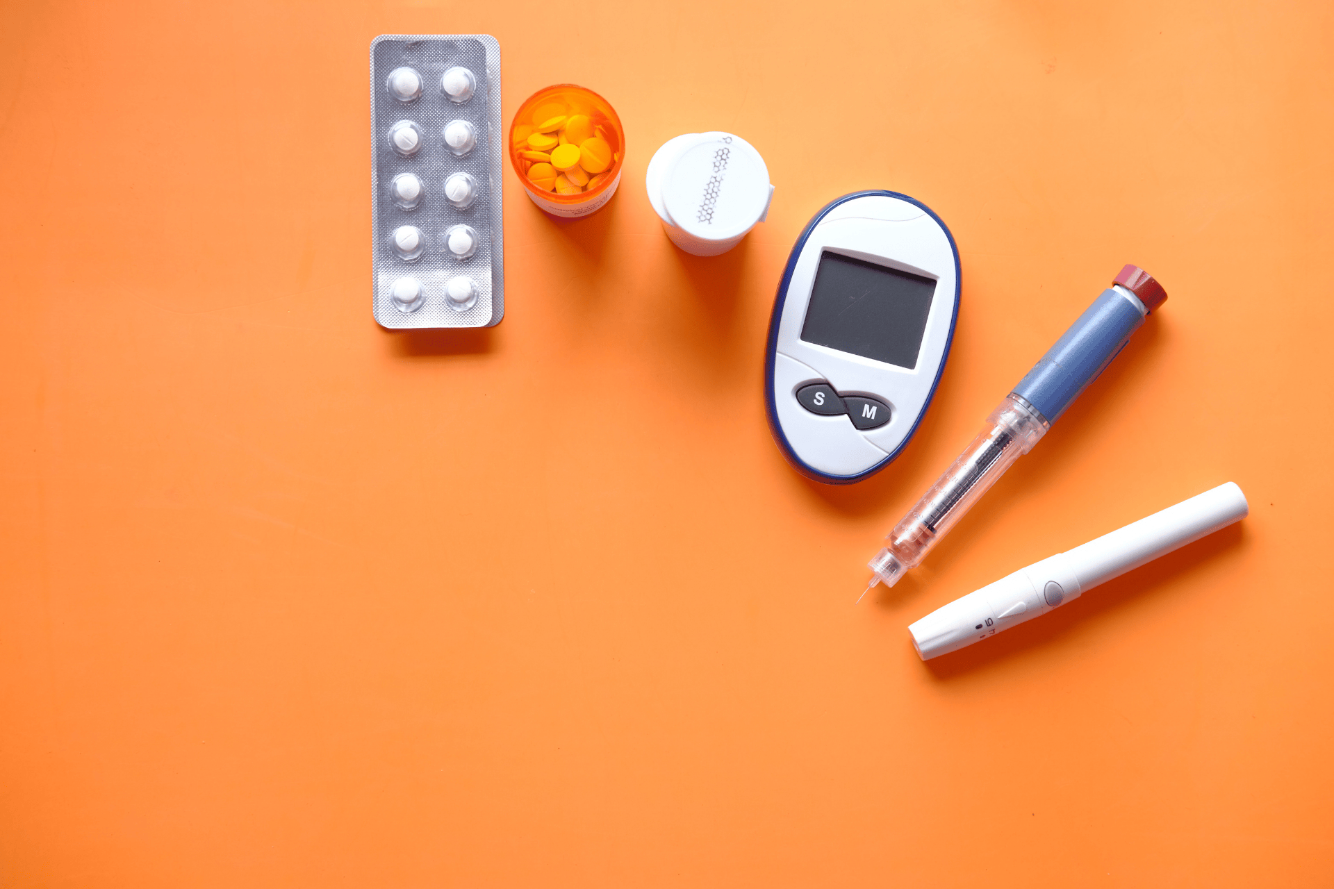 Diabetes care supplies: glucose meter, insulin pen, and medication on an orange background.