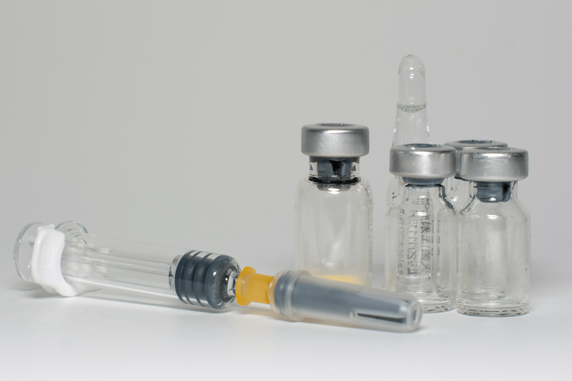 Medical vials and syringes arranged on a clean surface, representing injectable medications.