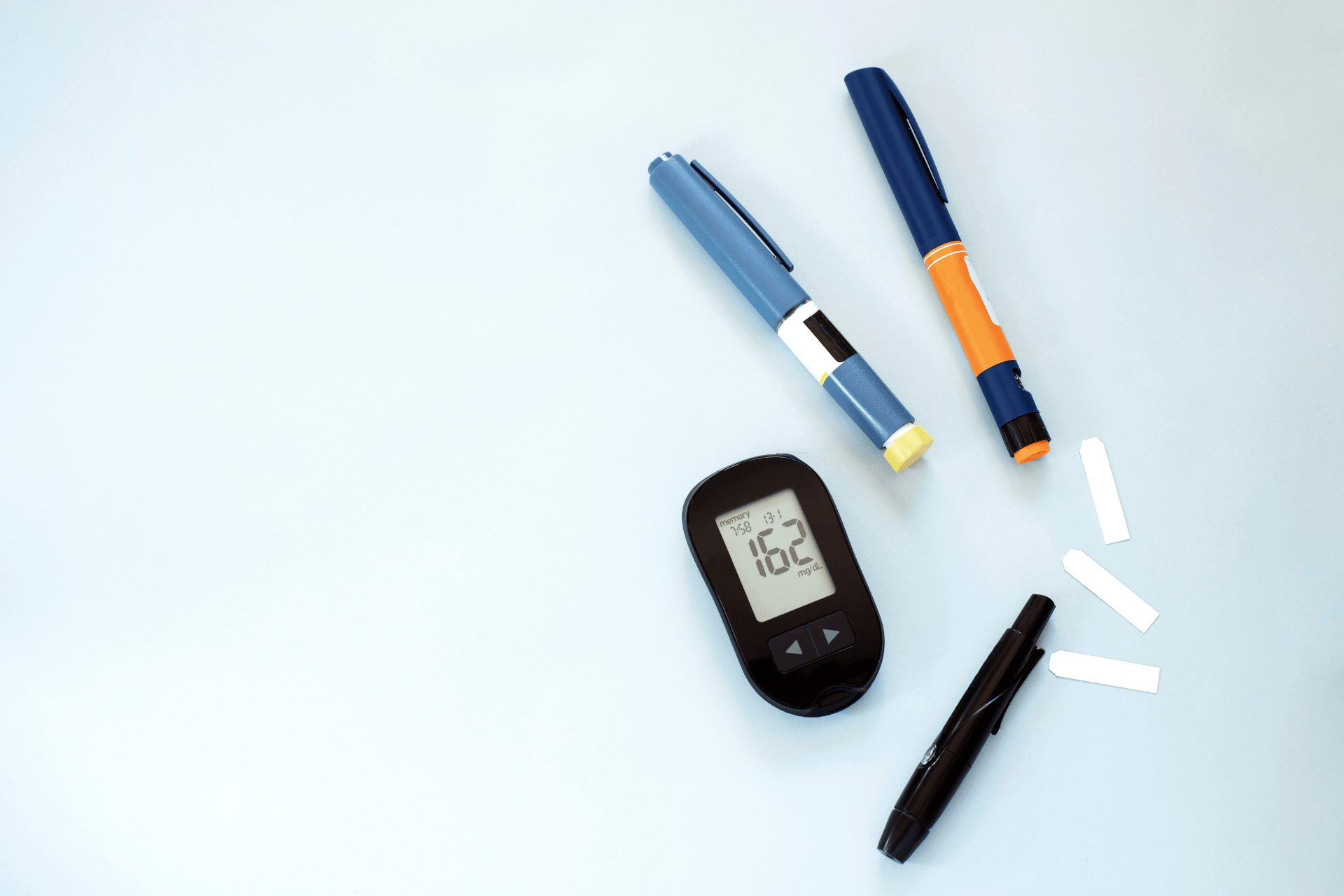 Diabetes management tools including a blood glucose meter, insulin pens, lancet, and test strips.
