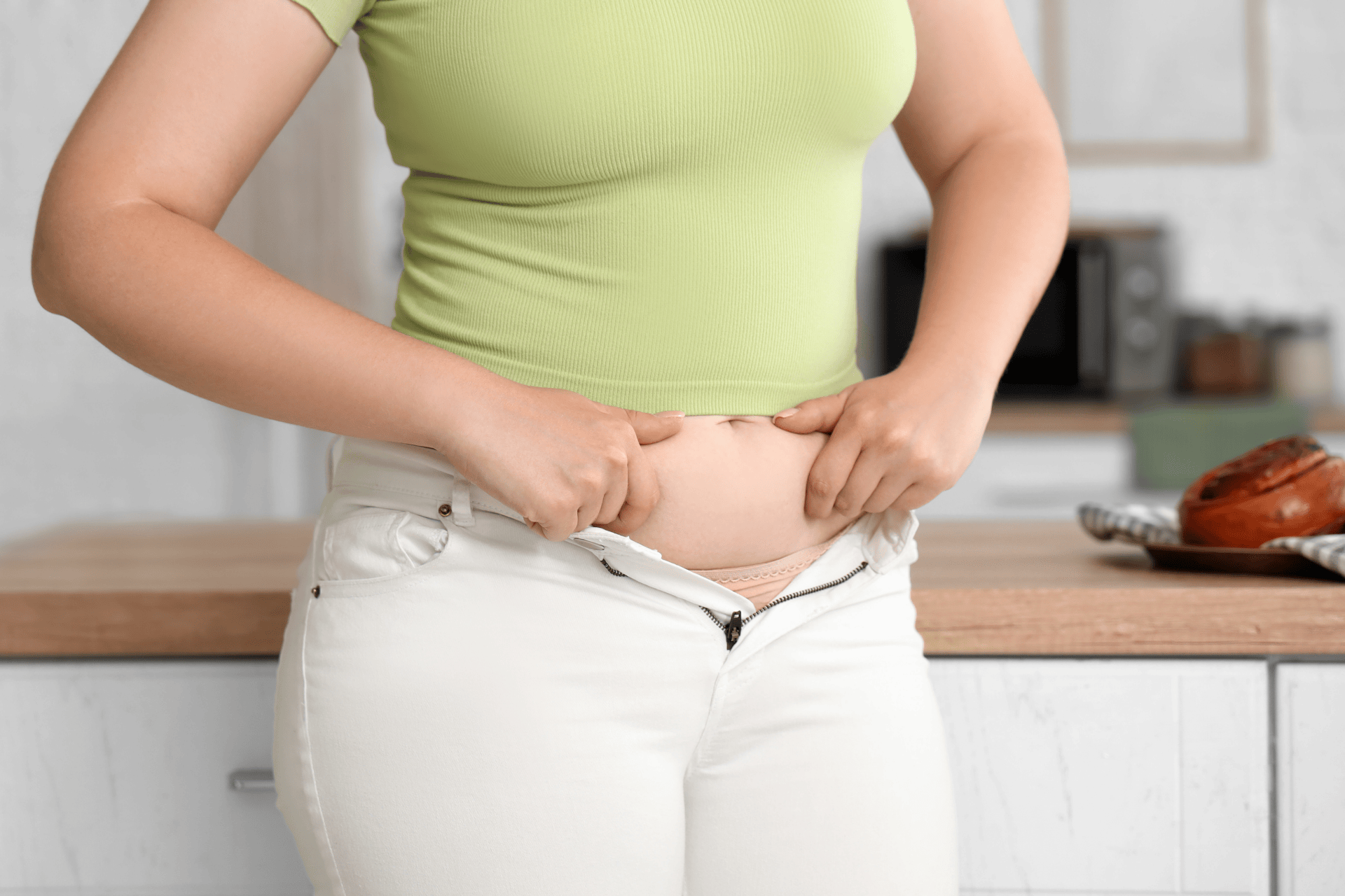 Person noticing weight gain by checking increased abdominal fat around the waist.