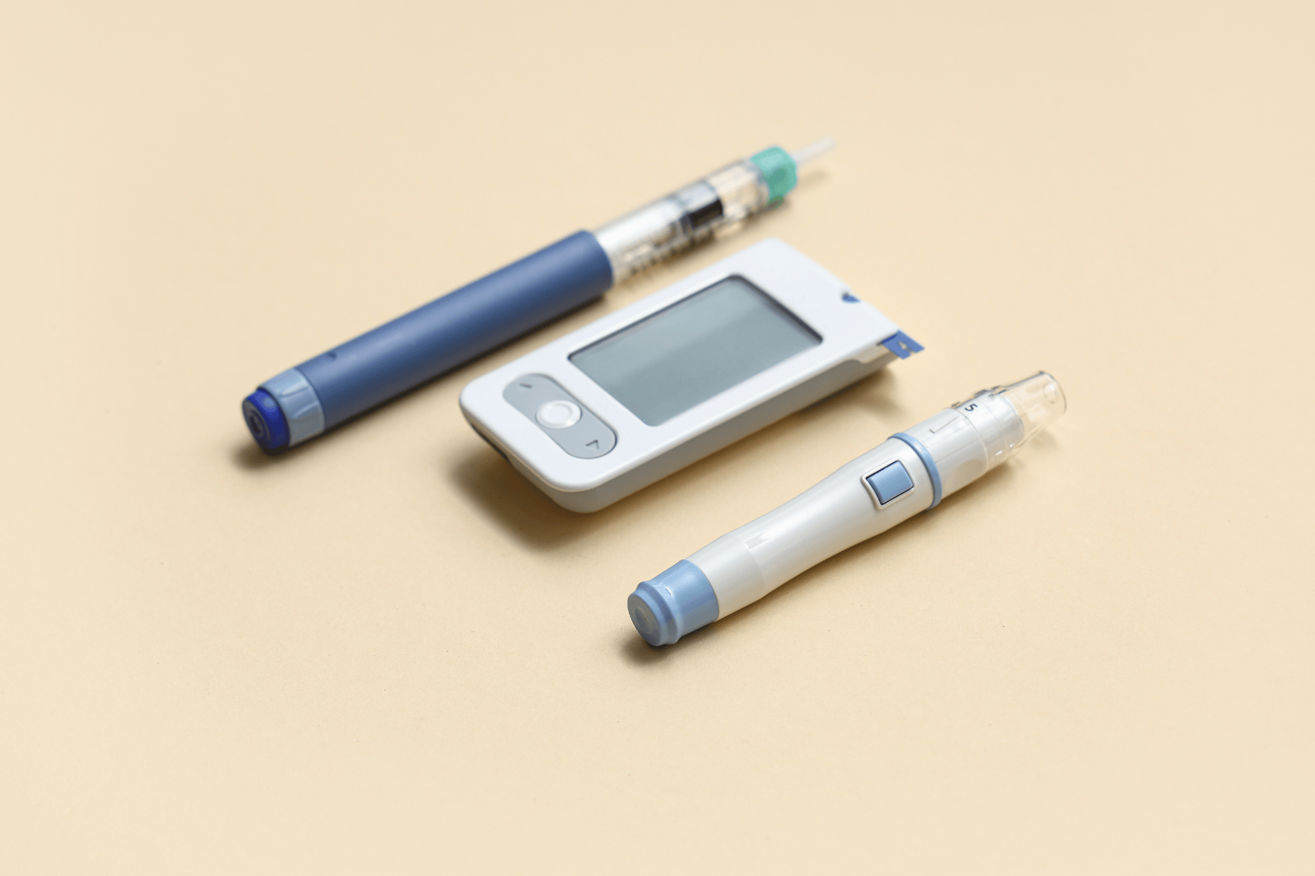 Diabetes tools, including insulin pens and a blood glucose meter, on a light surface.