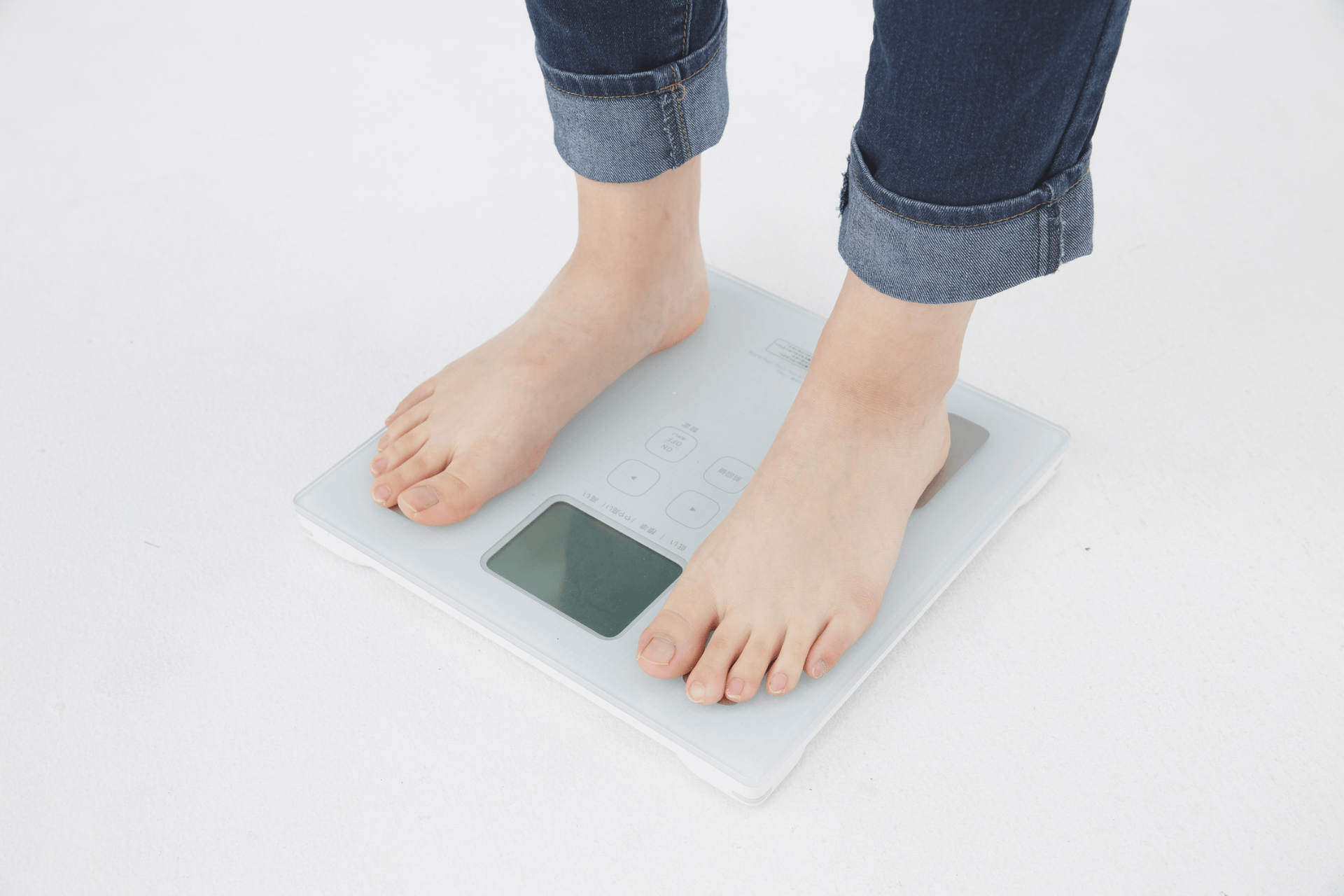 Person standing barefoot on a digital bathroom scale.