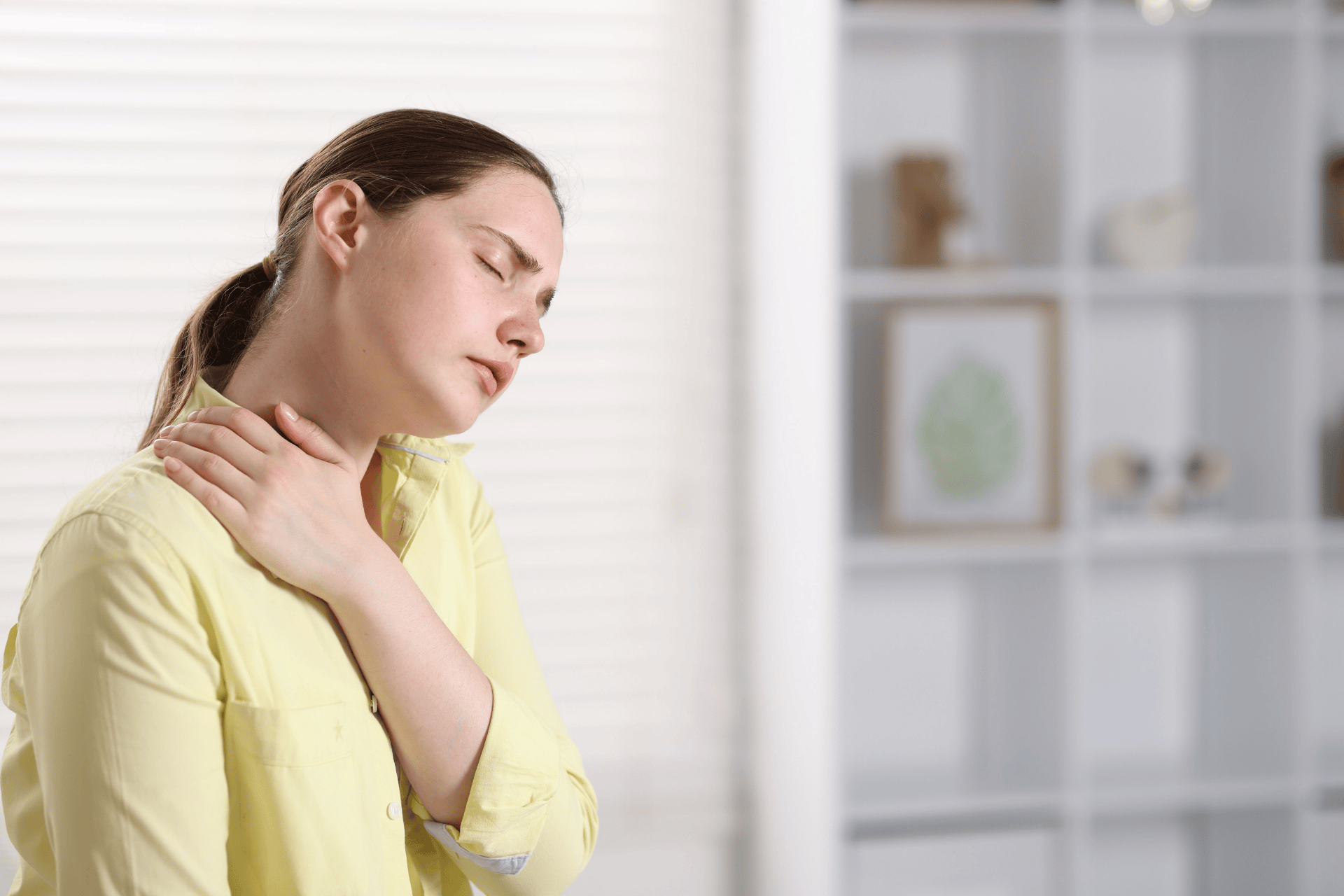 Woman holding her neck with eyes closed, showing fatigue and muscle aches.