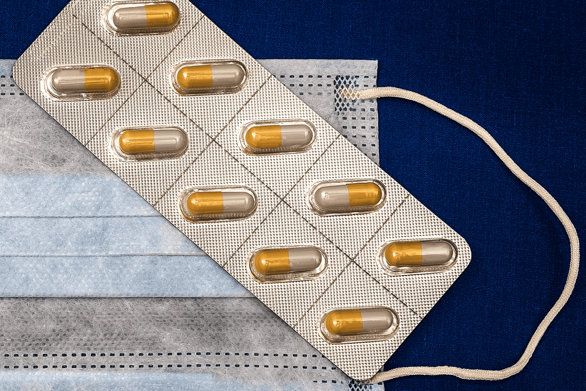 Blister pack of yellow-and-white capsules placed on top of disposable face masks.