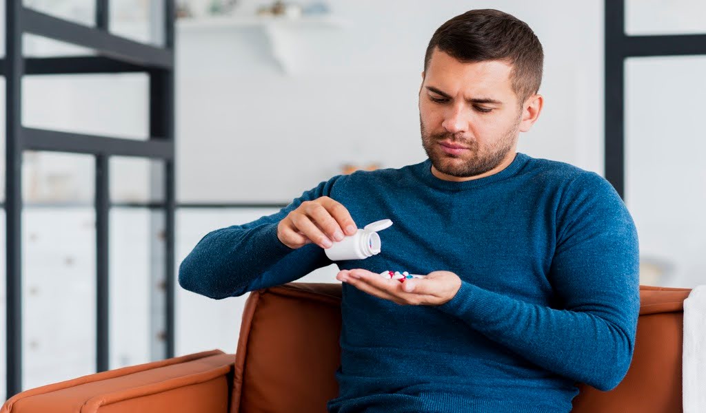 Focused man inspecting a stream of Vicodin pills pouring from a container