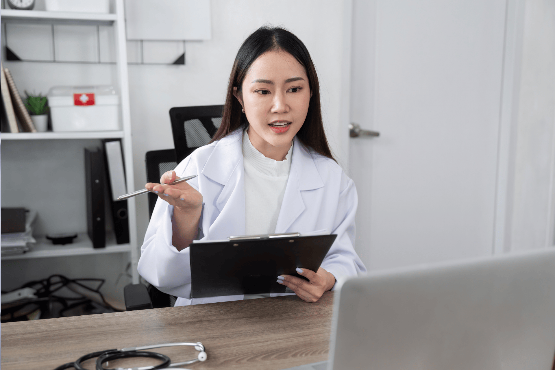 Doctor holding a clipboard and talking during an online consultation.