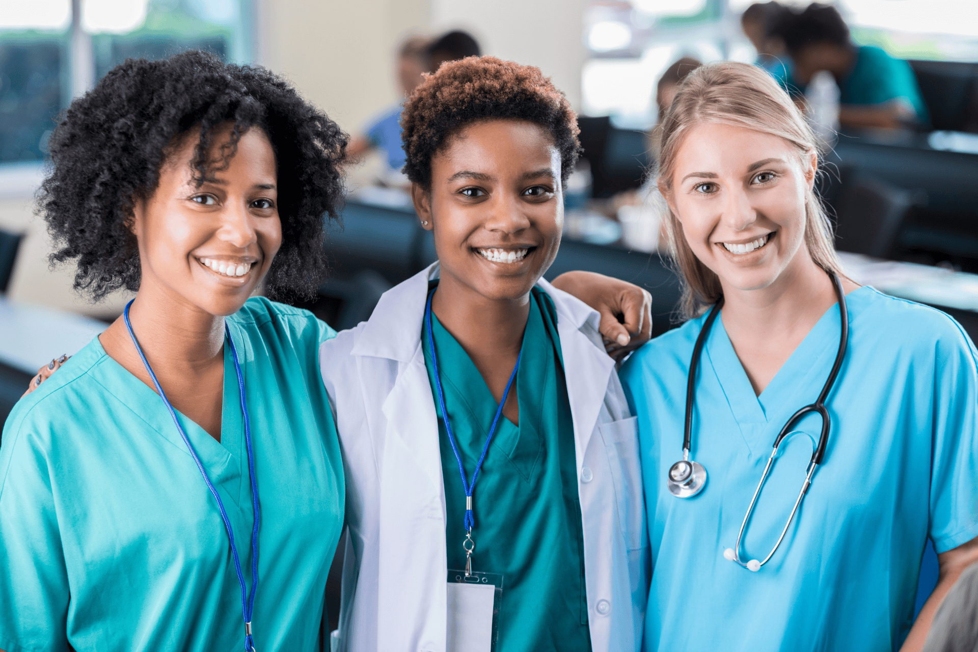 Three smiling healthcare professionals standing together in scrubs.