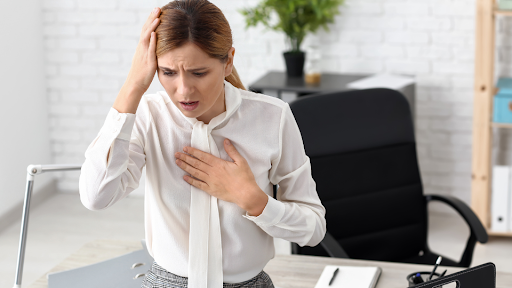 Woman at work with left hand on chest and right hand on head