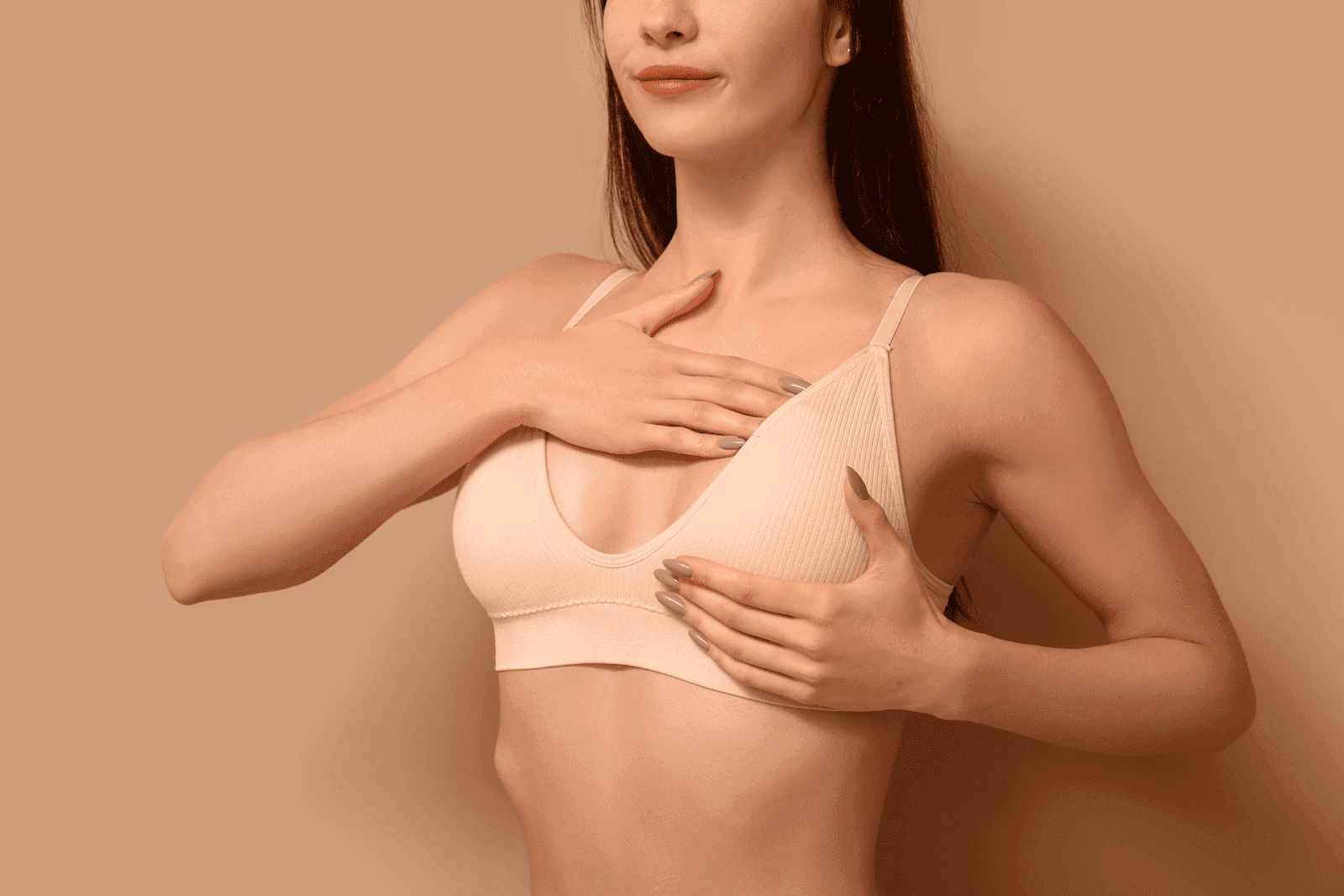 Woman checking her breast while wearing a bra.