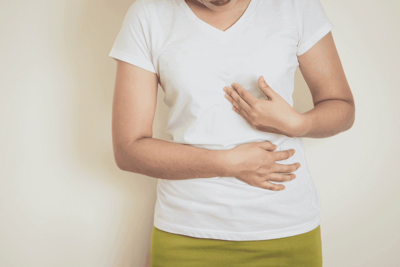 Woman clutching her stomach and chest, indicating thoracic or digestive discomfort