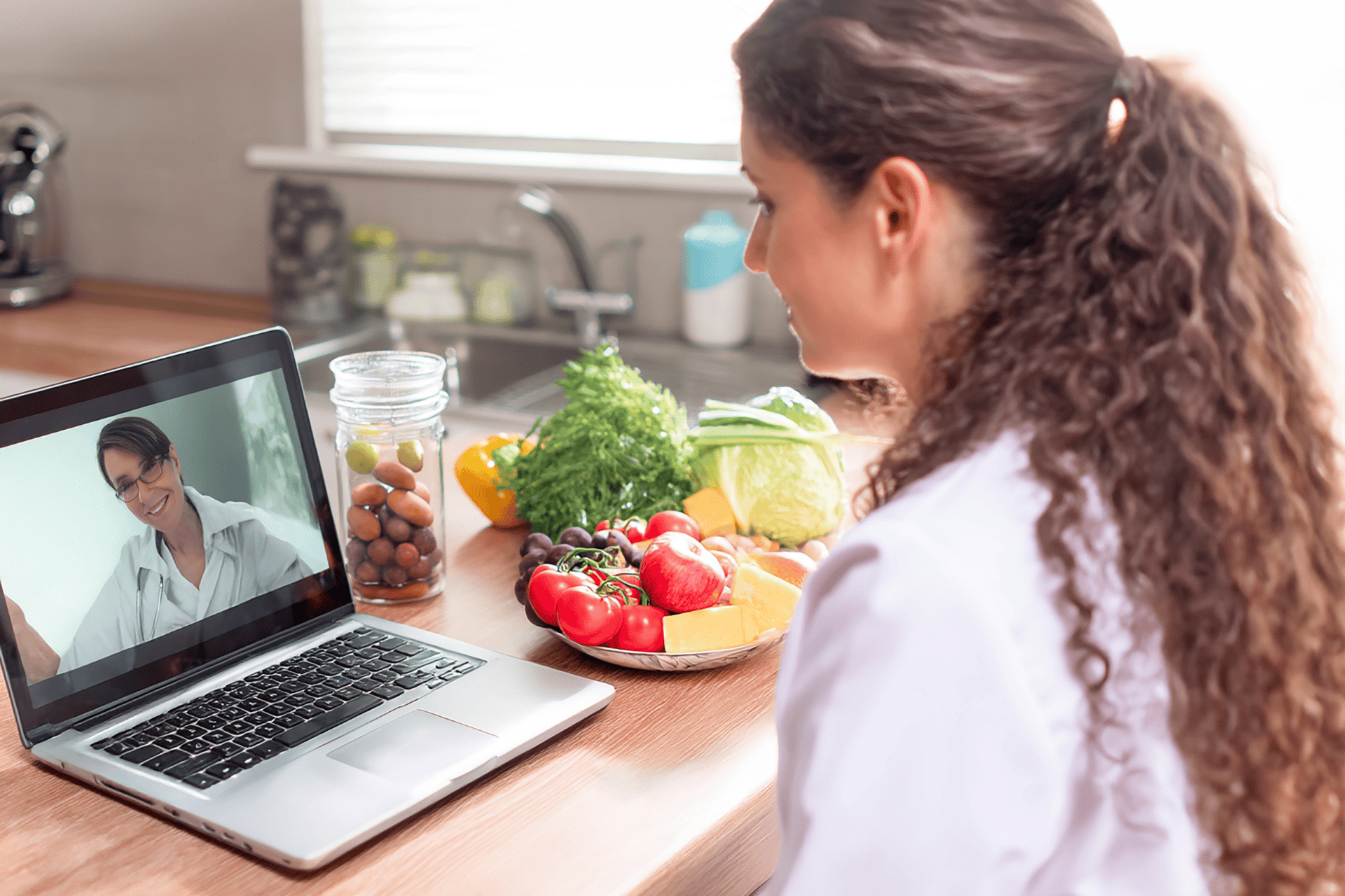 Woman consulting a doctor online about nutrition with fresh vegetables on the table