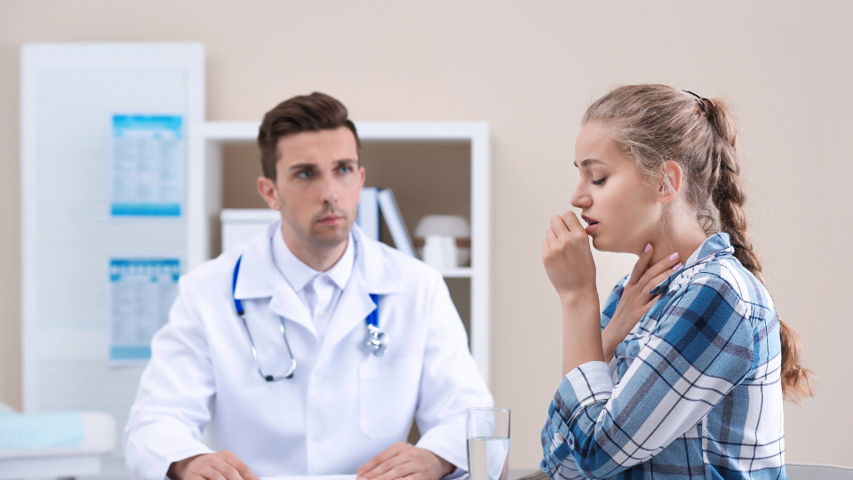 Woman coughing in front of doctor.